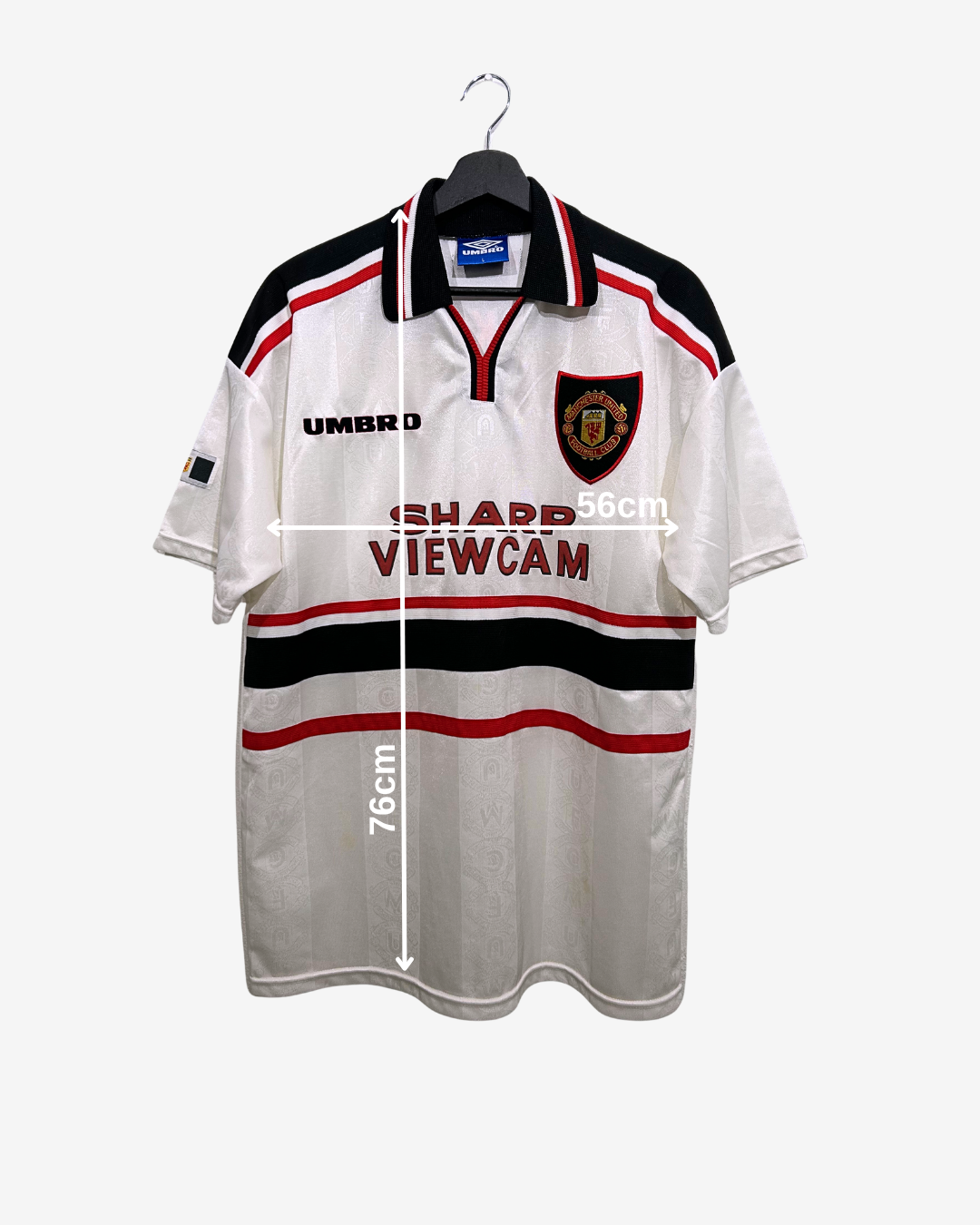 White sports jersey with black and red accents on a hanger, featuring Umbro branding.