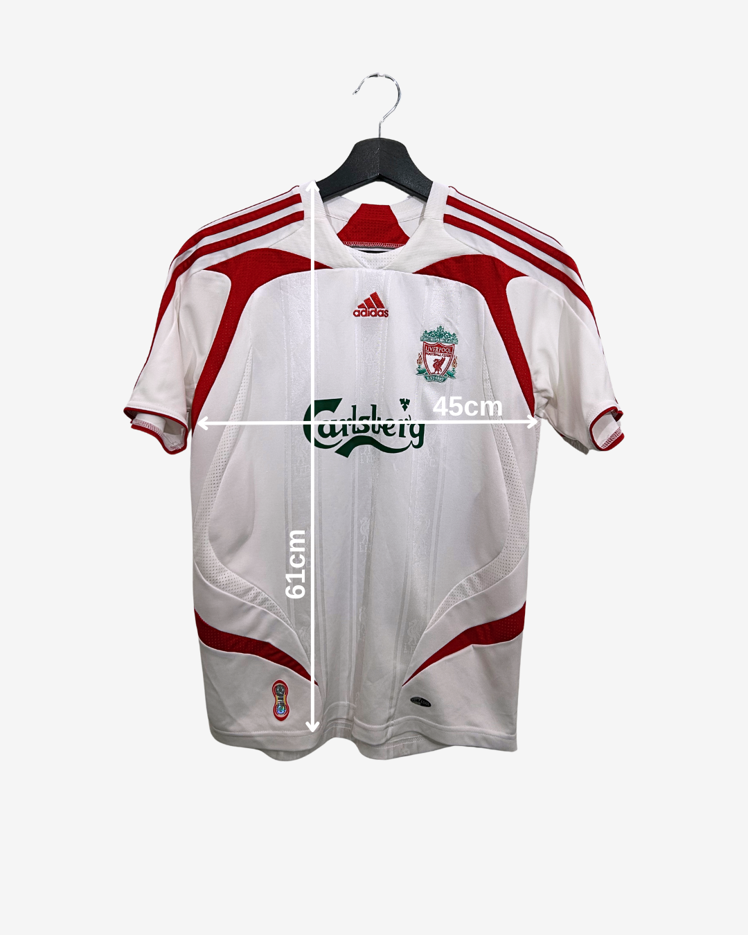 White sports jersey with red accents on a hanger, featuring Adidas and Liverpool FC logos, with measurements indicated.