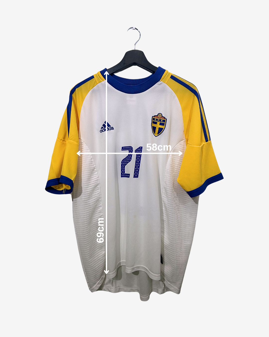 White sports jersey with yellow sleeves and blue collar on a hanger, featuring Adidas logo and Swedish flag design.