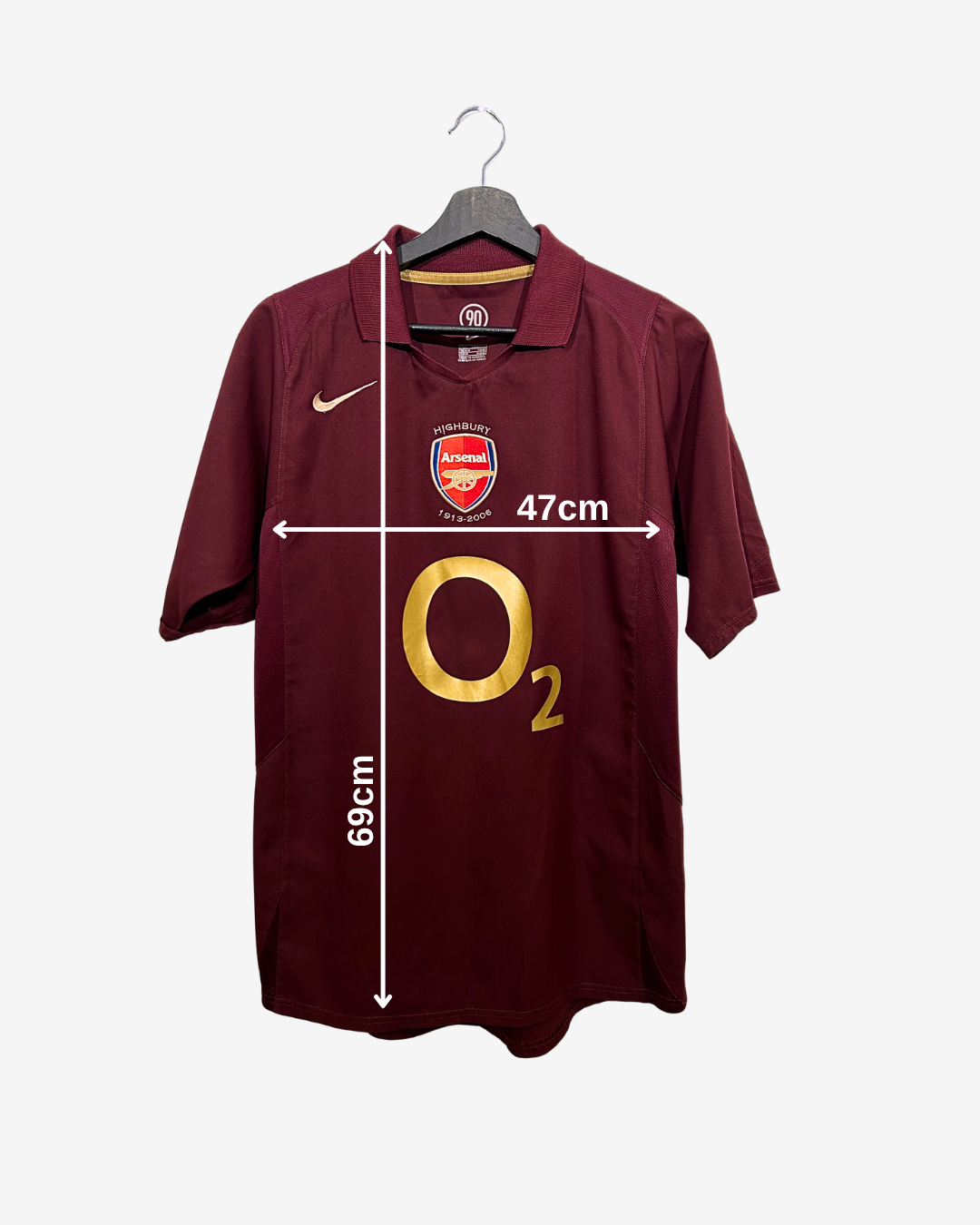 Maroon Arsenal football shirt on a hanger with measurements indicated.