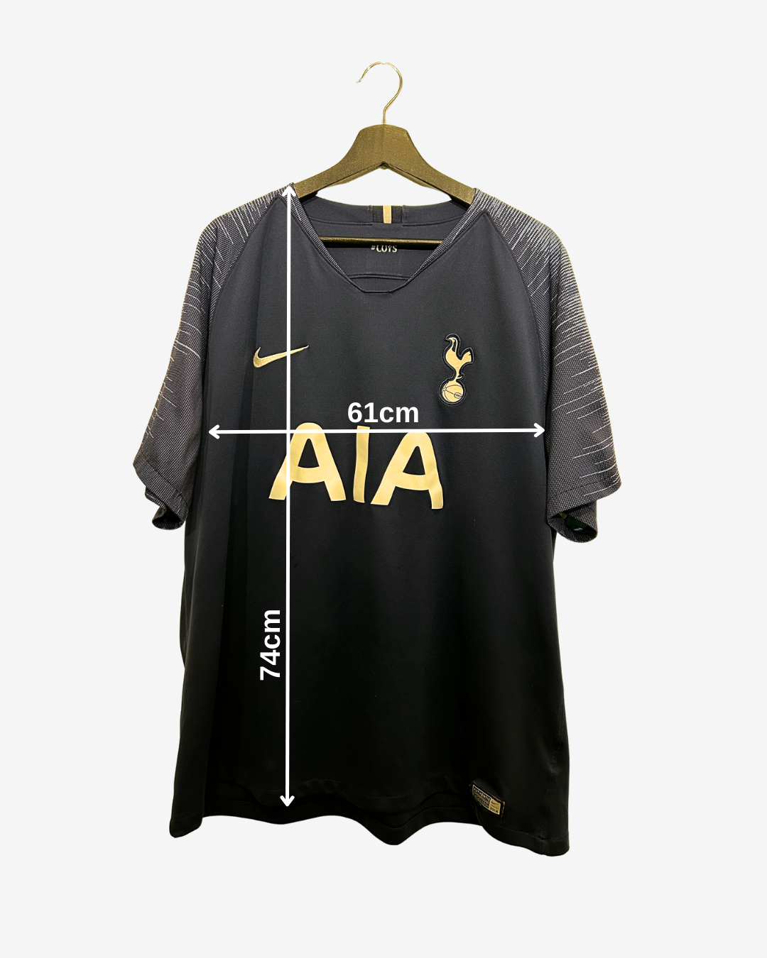 Black sports jersey with gold branding on a hanger, showing measurements.