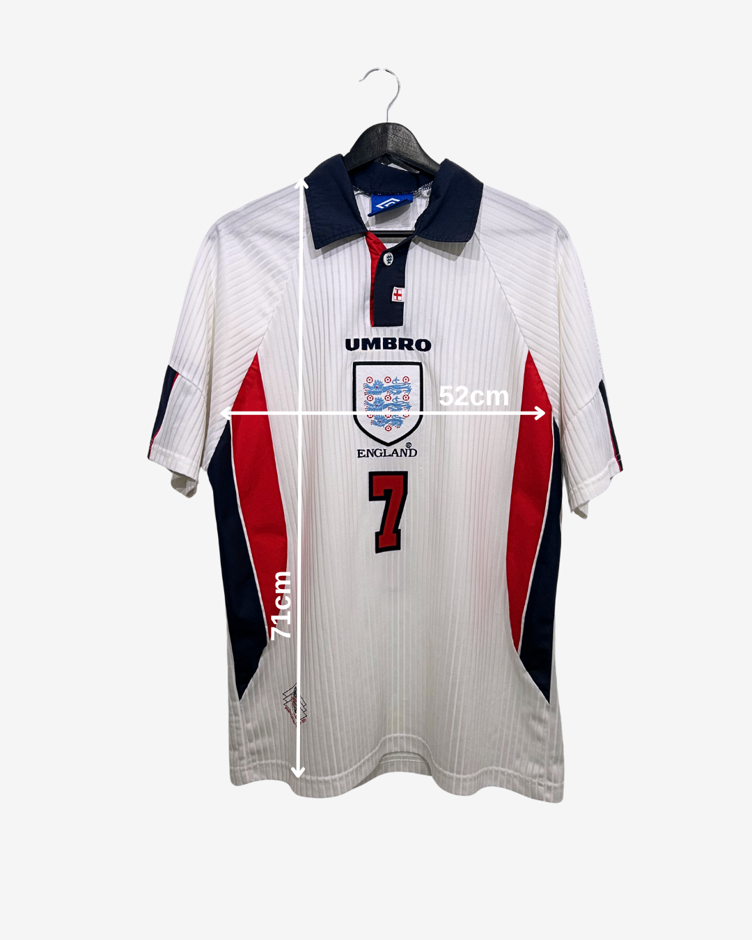 White sports jersey with red and blue accents on a hanger, featuring Umbro branding.