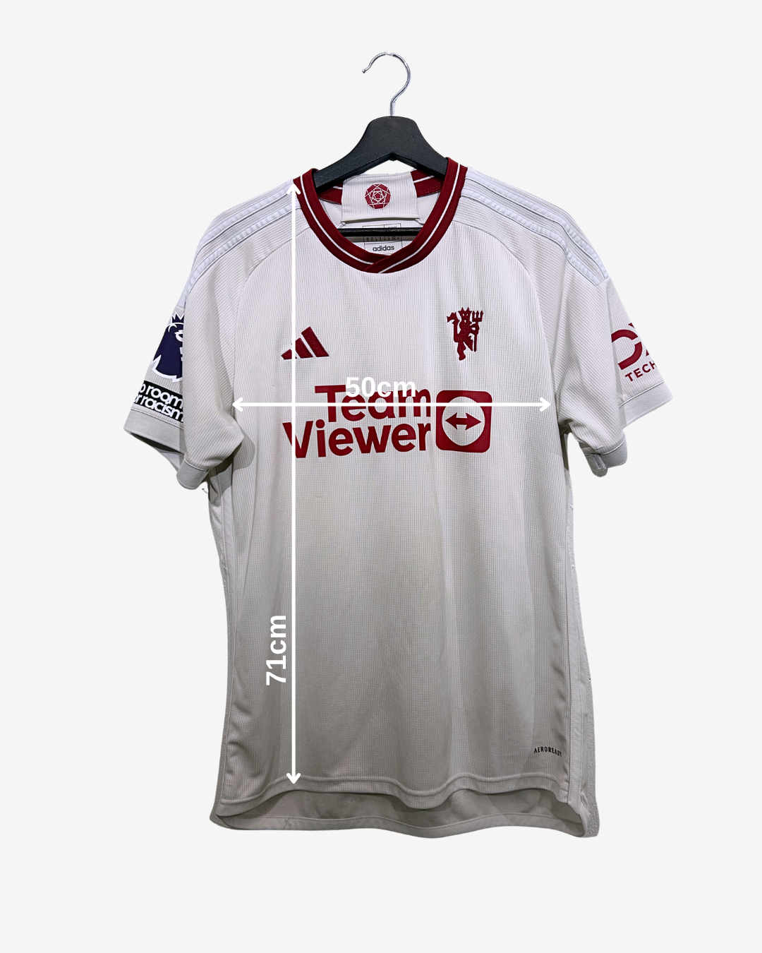 White sports jersey with red accents on a hanger, featuring brand logos.