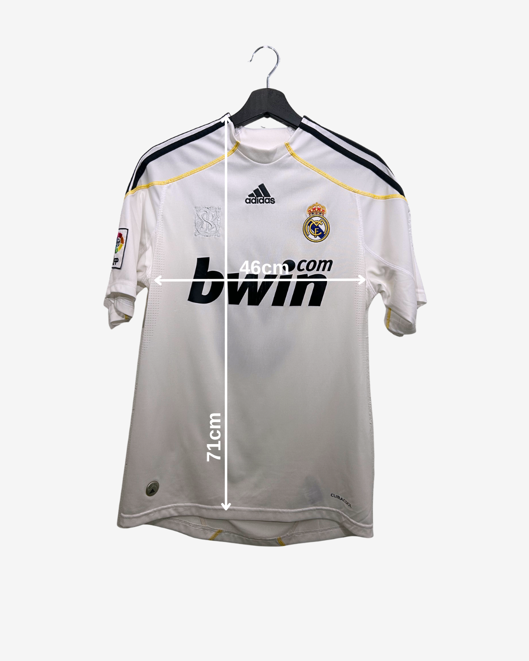 Real Madrid jersey with Adidas logo on a hanger, measurement details included.
