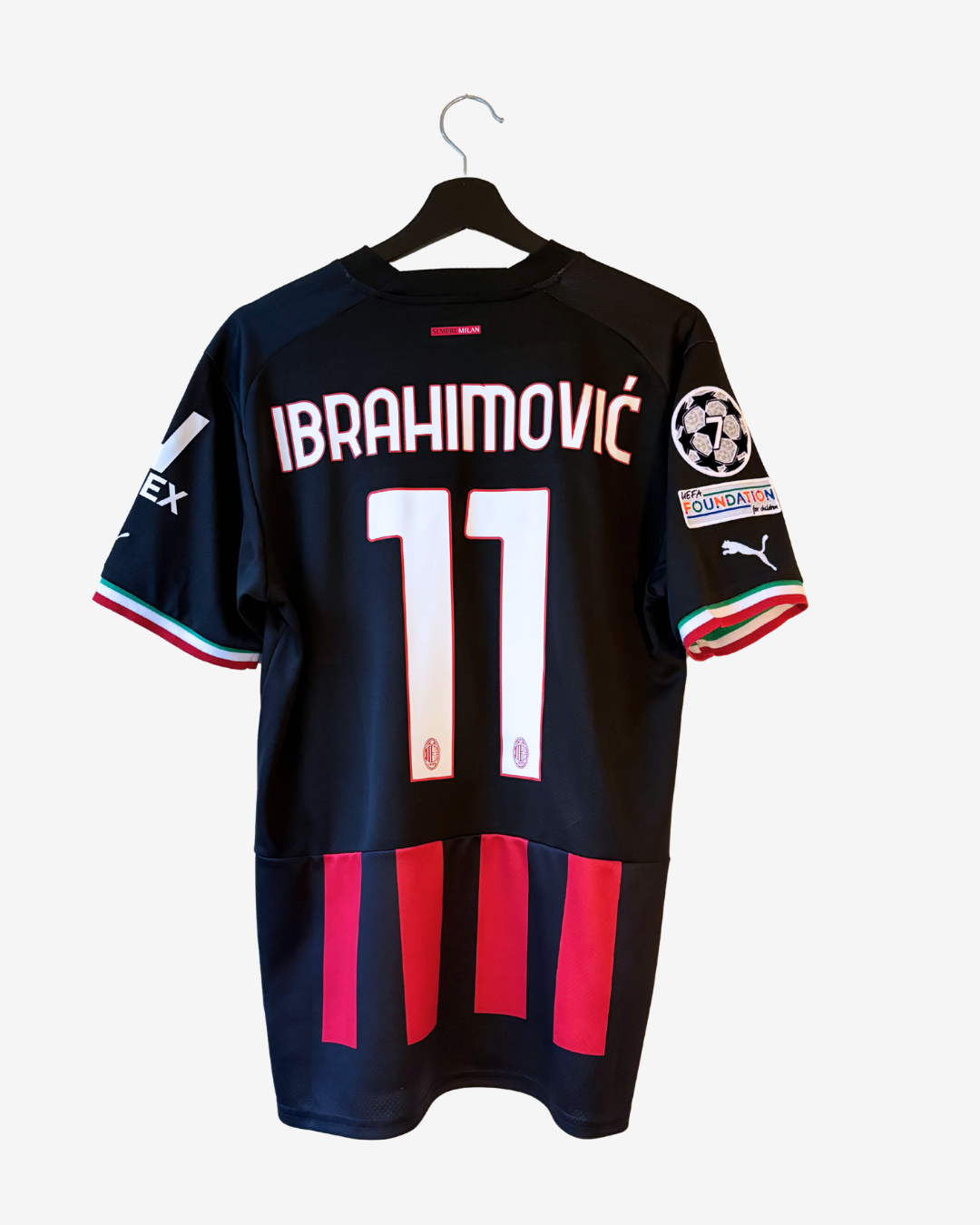 Black Puma AC Milan football jersey with Ibrahimovic number 11 on the back, featuring red and white vertical stripes at the bottom and Italian flag trim on the sleeves.