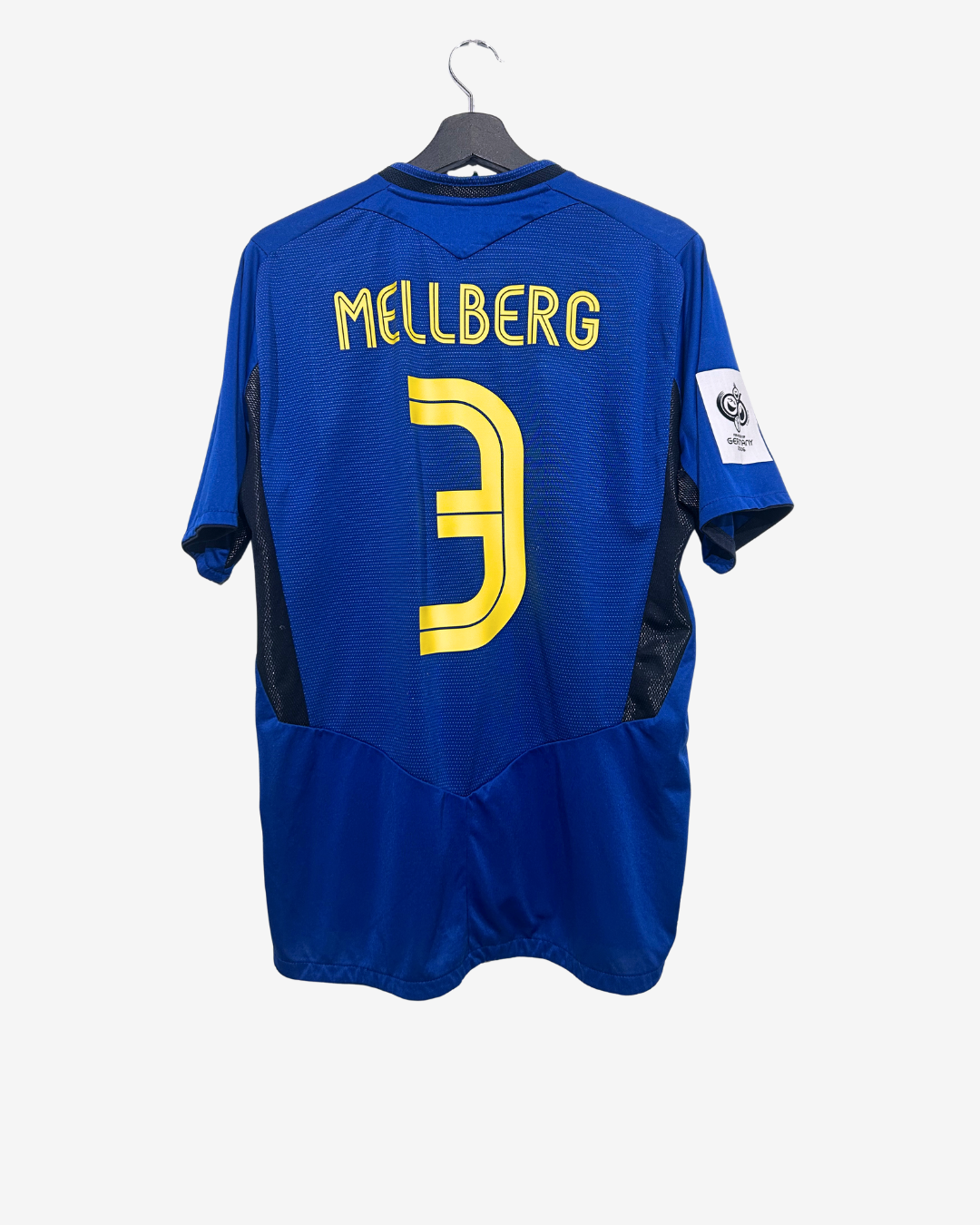 Blue sports jersey with 'Mellberg' and number '3' on a hanger against a white background