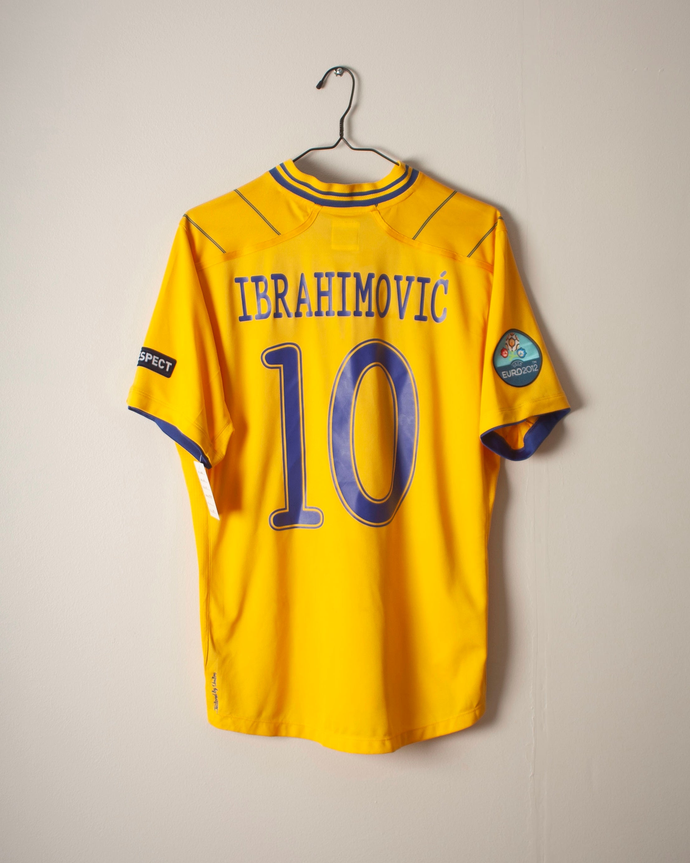 Yellow sports jersey with 'Ibrahimovic' and number '10' on a hanger against a plain background