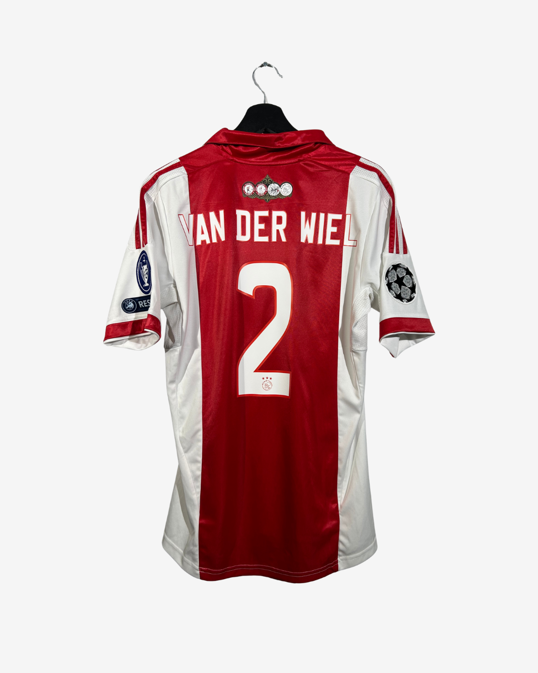 A red and white Netherlands national football team jersey with 'VAN DER WIEL' and the number '2' on the back, hanging on a black hanger against a light gray background.