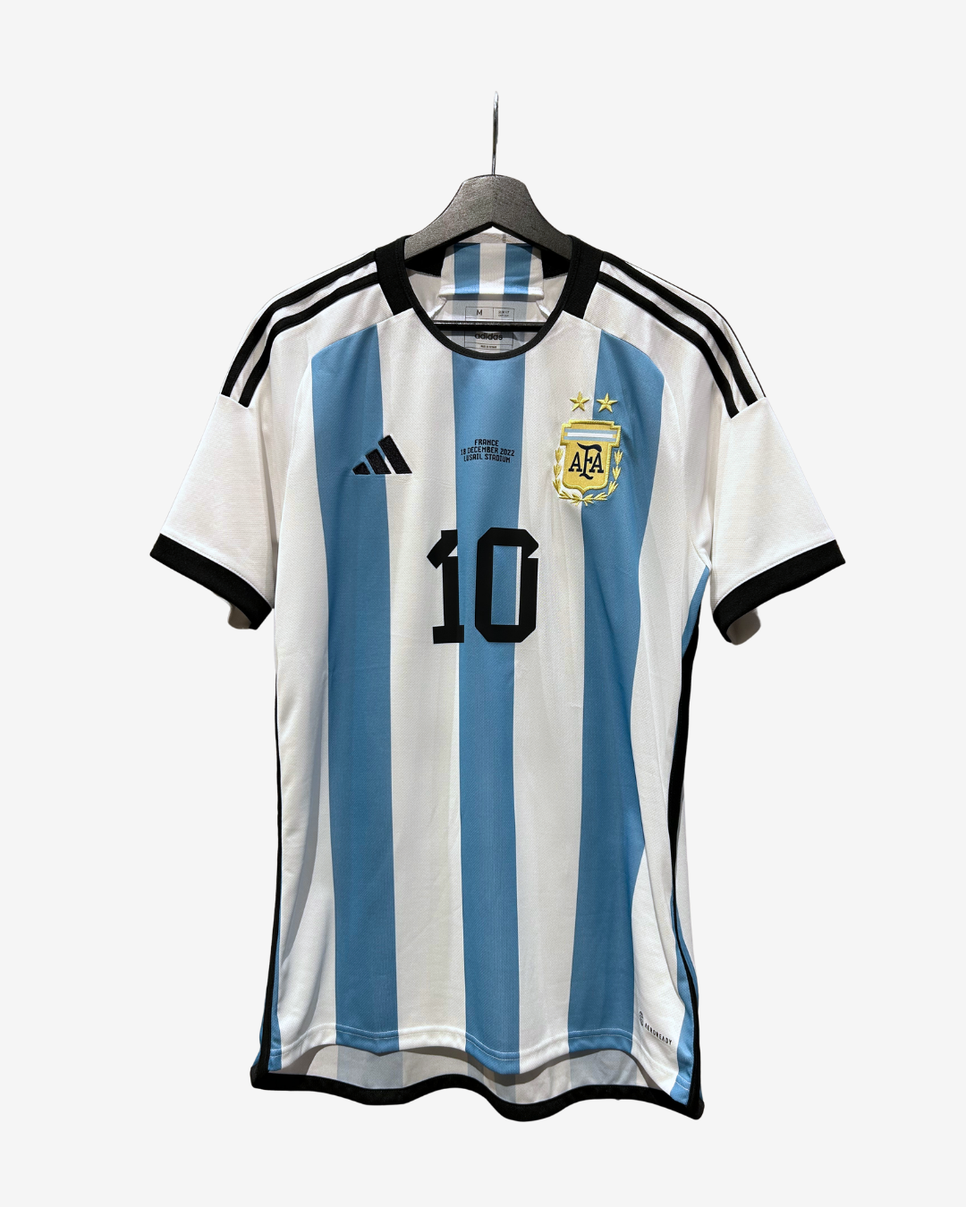 Argentina national football team home jersey with light blue and white vertical stripes, black trim, the number 10 on the front, and the Adidas logo. The jersey is displayed on a hanger against a light gray background.