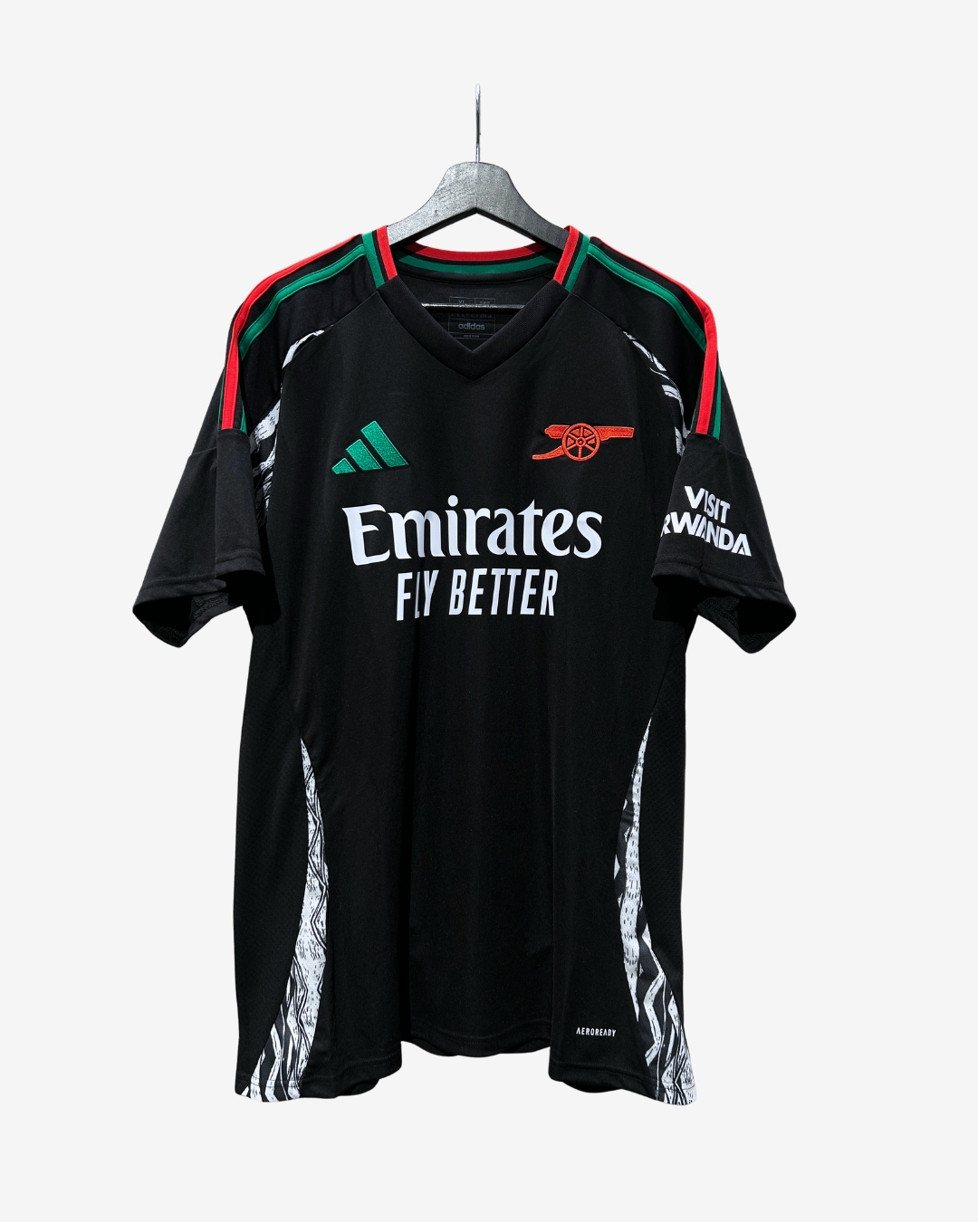 A black Arsenal football jersey with green and red shoulder stripes, featuring the Emirates Fly Better sponsor logo, Adidas logo, and Arsenal crest, hanging on a gray hanger against a light gray background.