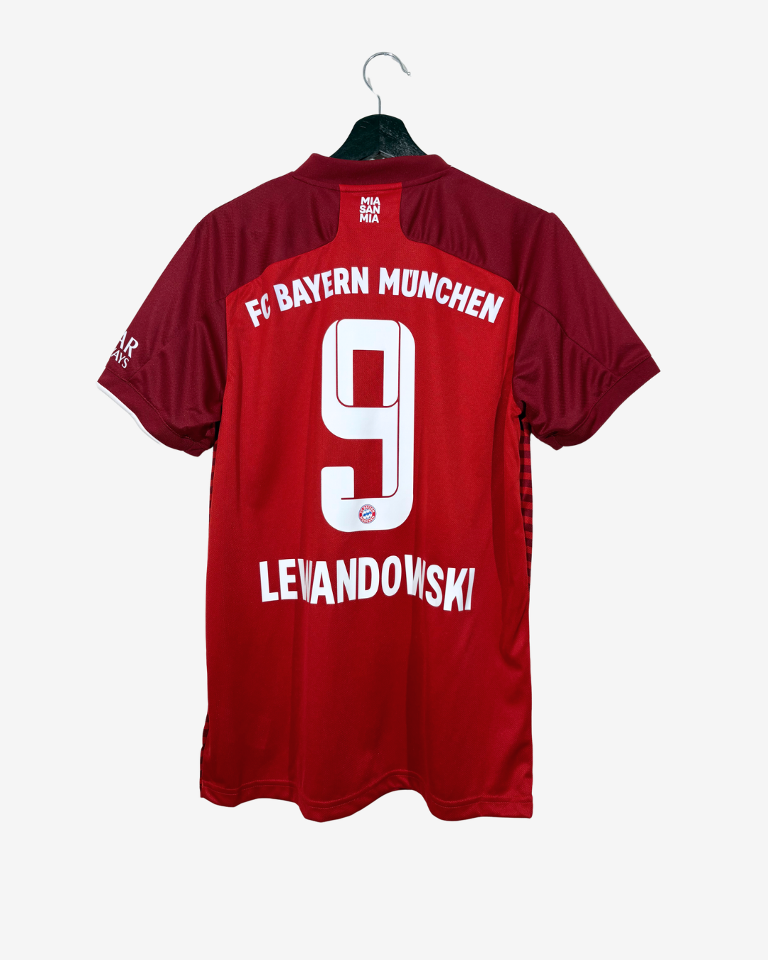 A red and dark red short-sleeve soccer jersey hanging on a black hanger against a light gray background. The back of the jersey features 'FC BAYERN MÜNCHEN' in white text, a large white number '9', and the name 'LEIANDOWSKI' below.