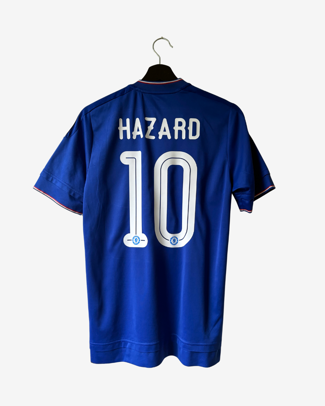 A royal blue short-sleeve soccer jersey hanging on a black hanger against a light gray background. The back of the shirt features the name 'HAZARD' and the number '10' in white with a light blue outline.