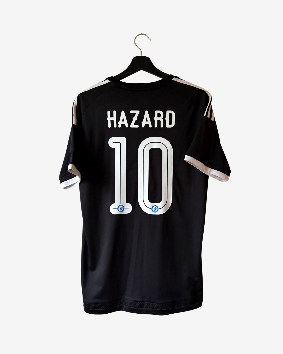 Black soccer jersey with 'HAZARD 10' printed on the back, hanging on a black hanger against a light gray background.