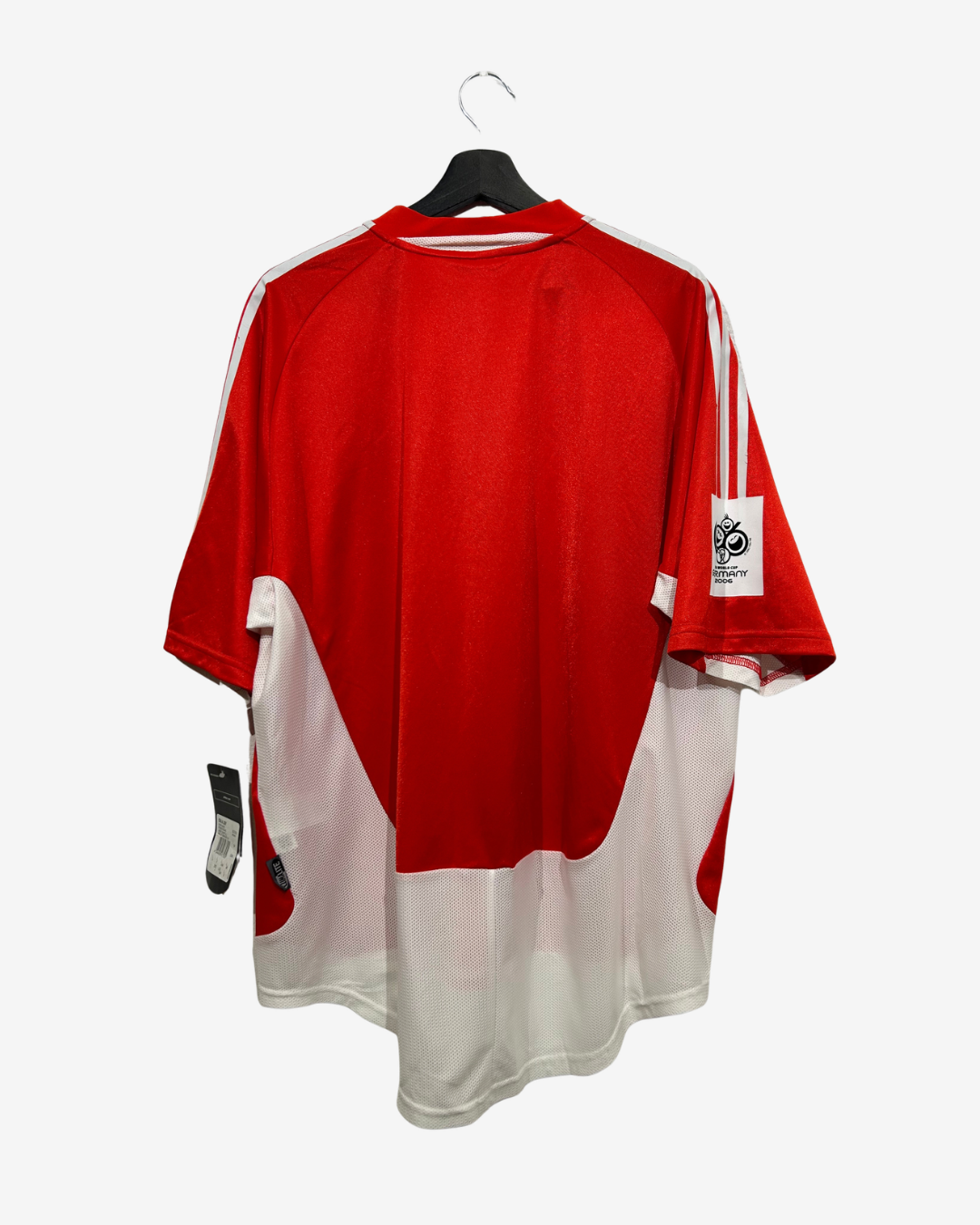 A red and white athletic jersey hanging on a black hanger against a light gray background. The back of the shirt features a large red panel with white curved accents, white shoulder stripes, and a white patch on the right sleeve.