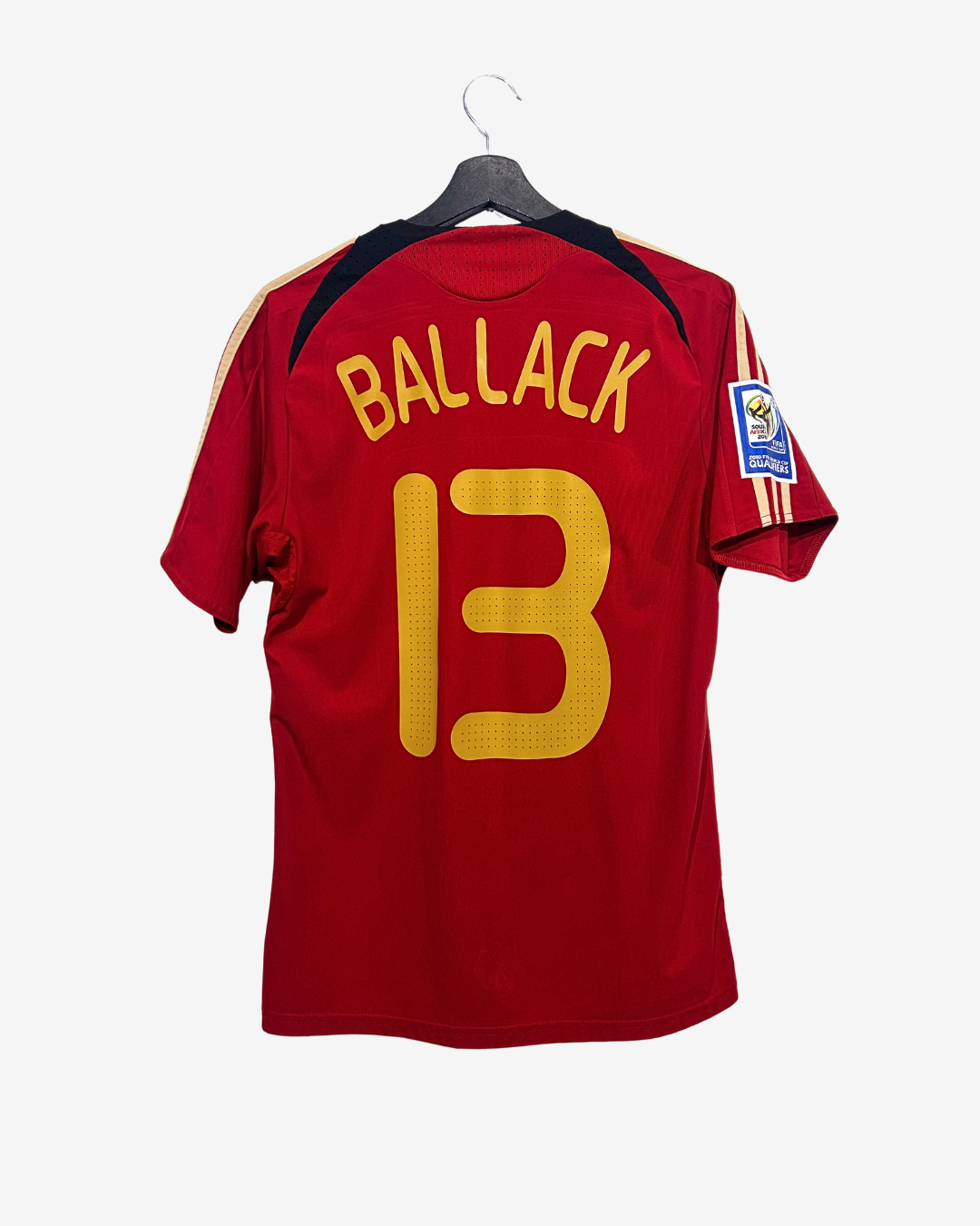 Red sports jersey with 'BALLACK' and number '13' on a hanger against a white background
