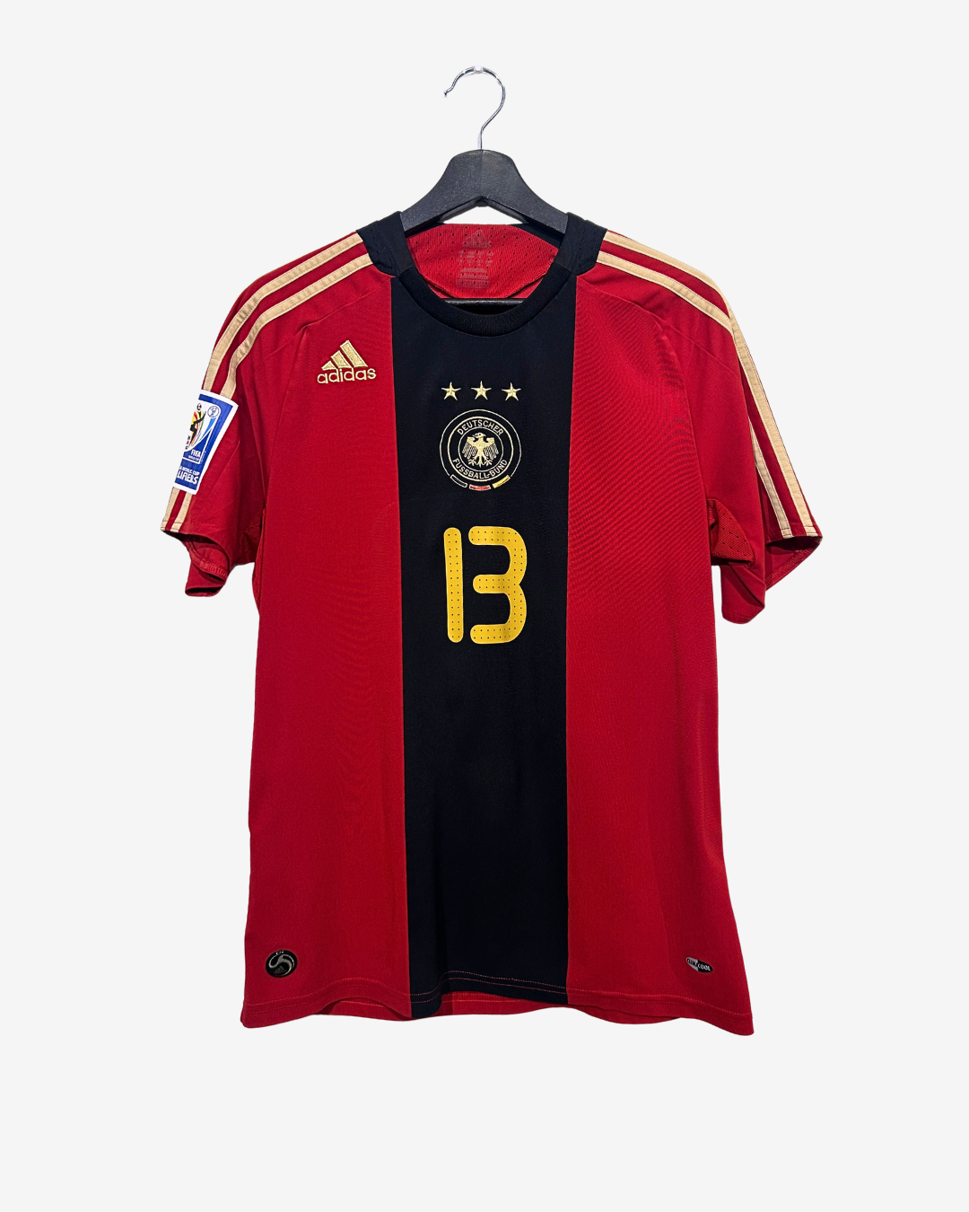Red and black sports jersey with yellow number 13 on a hanger against a white background