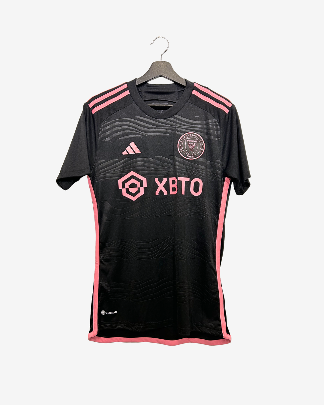 Black sports jersey with pink accents and branding on a hanger against a white background