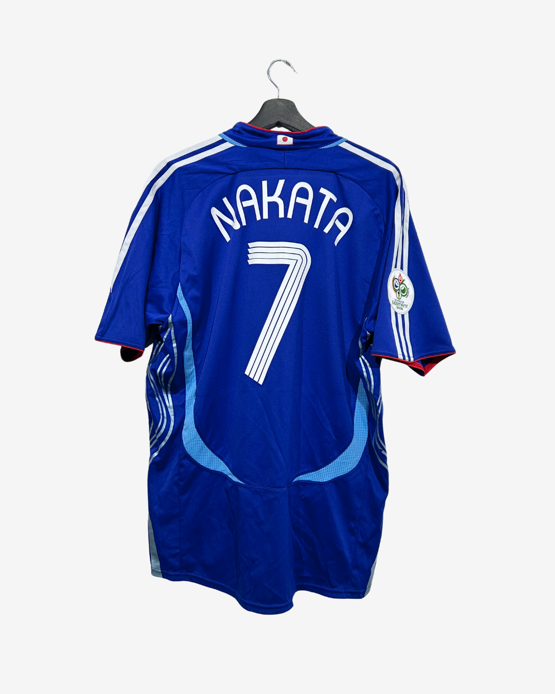 A blue soccer jersey with 'NAKATA' and the number 7 printed on the back, hanging on a black hanger against a light gray background.