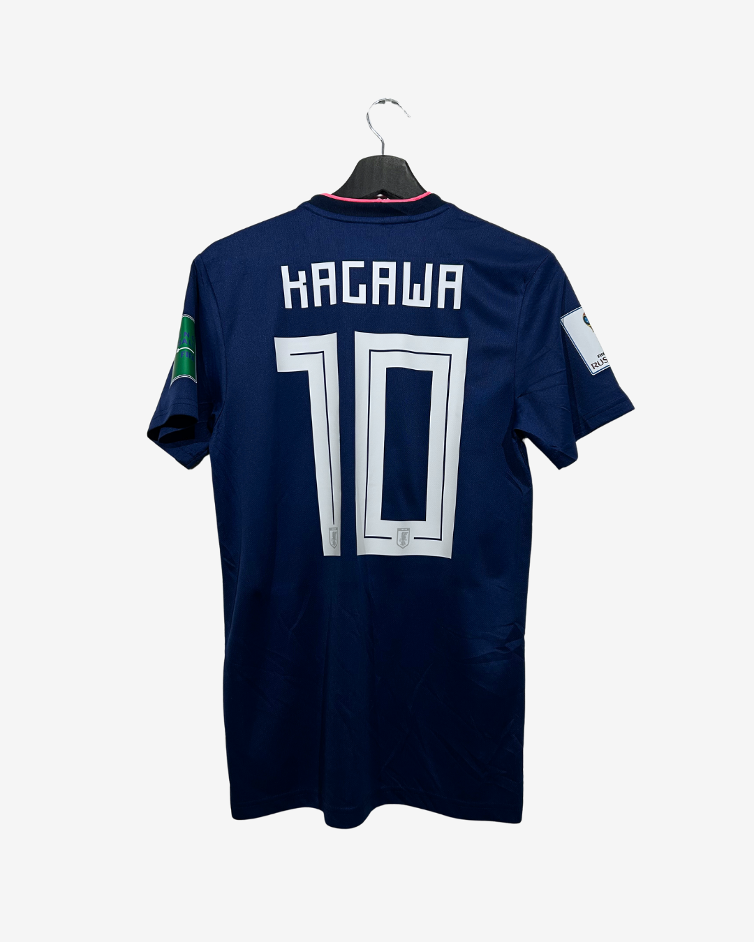 A navy blue soccer jersey with 'KAGAWA' and the number '10' printed in white on the back, hanging on a black hanger against a light gray background.