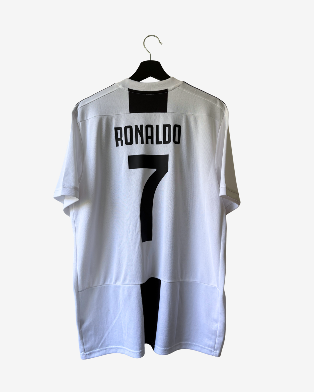 A white soccer jersey with black accents, featuring the name 'RONALDO' and number '7' on the back, hanging on a black hanger against a light gray background.