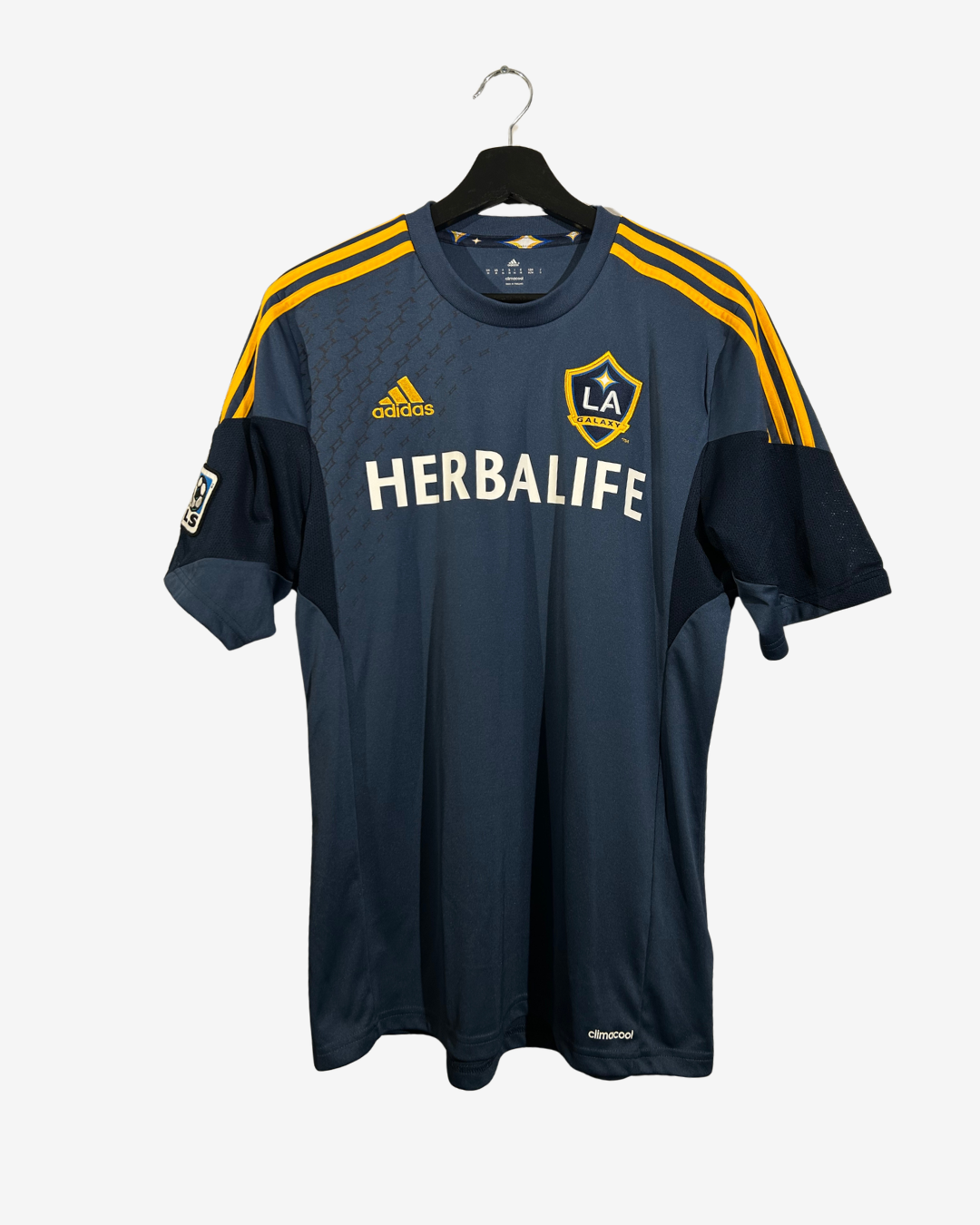 A navy blue Los Angeles Angeles FC soccer jersey by Adidas, featuring yellow shoulder stripes, a yellow LA crest, and a white Herbalife sponsor logo, hanging on a black hanger against a light gray background.