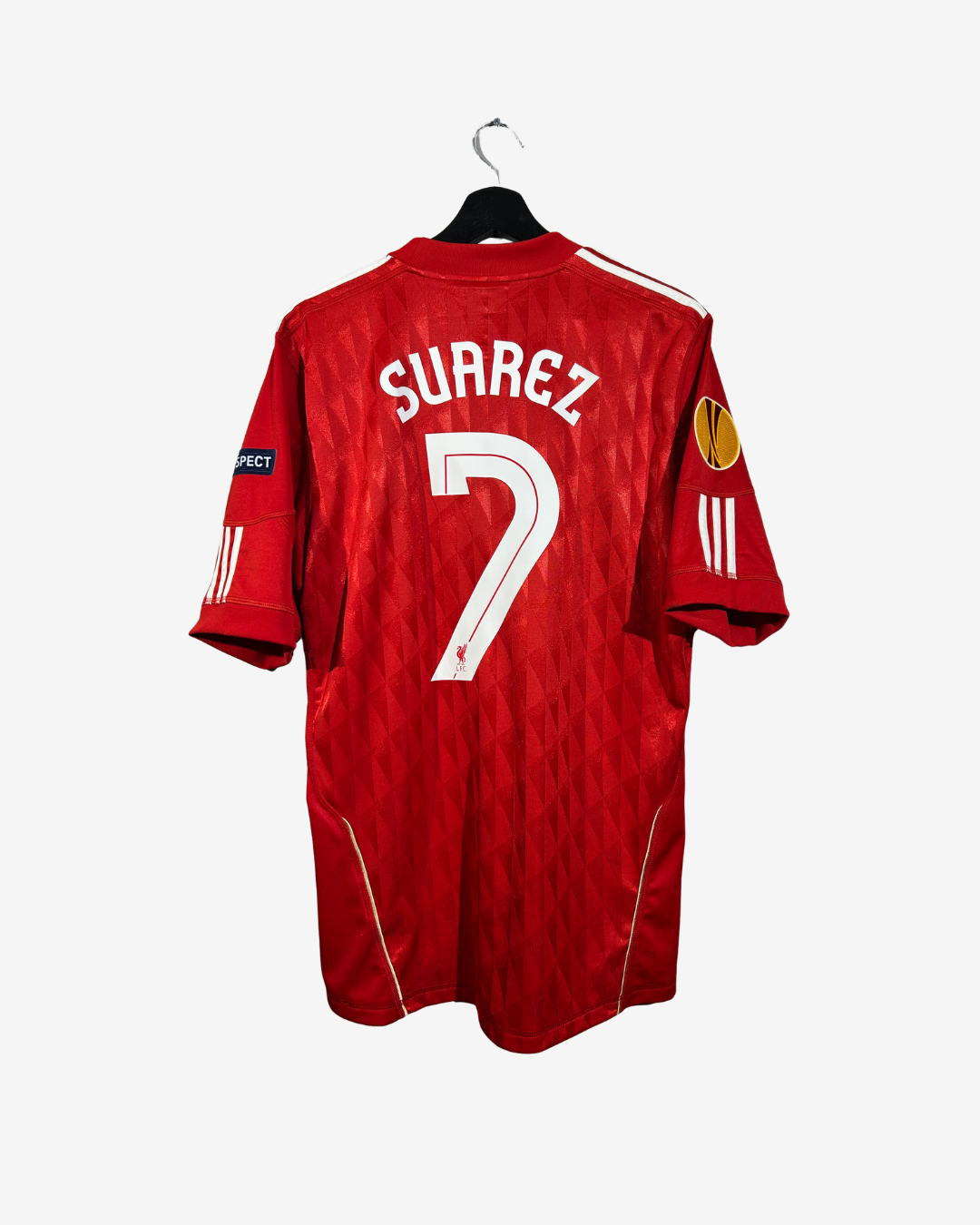 A red short-sleeve soccer jersey hanging on a black hanger against a light gray background. The back of the jersey features the name 'SUAREZ' and the number '7' in white, with Adidas branding visible on the sleeves.