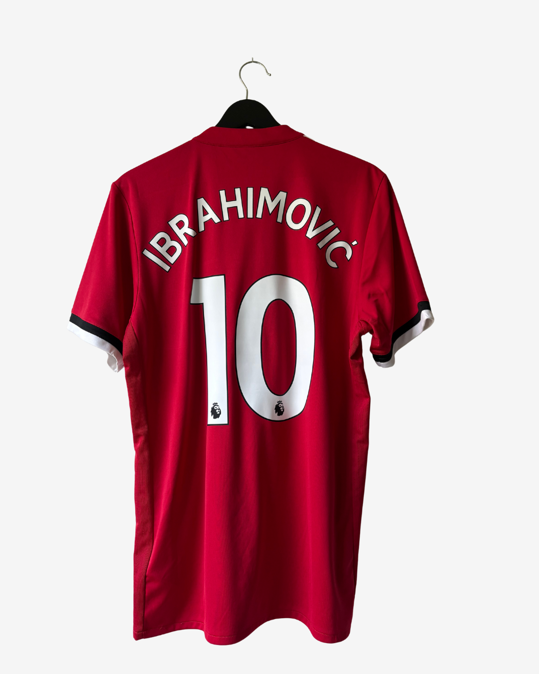 A red short-sleeve soccer jersey hanging on a black hanger against a light gray background. The back of the shirt features the name 'IBRAHIMOVIC' and the number '10' in white, with small black and white sleeve trim details.