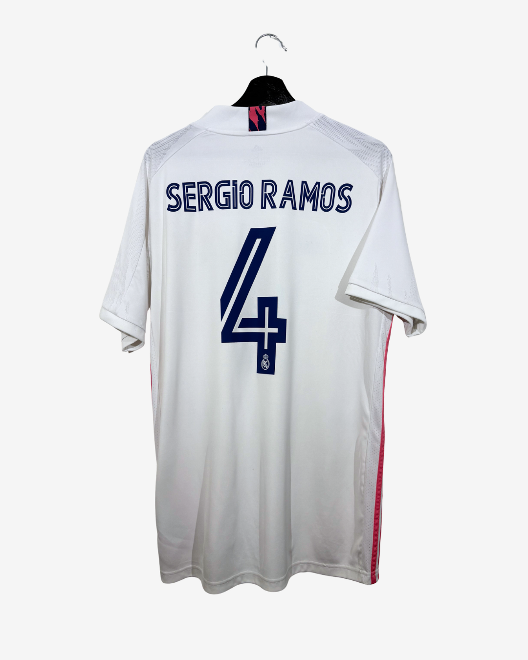 White soccer jersey with 'SERGIO RAMOS' and the number 4 printed in navy blue on the back, hanging on a black hanger against a light gray background.
