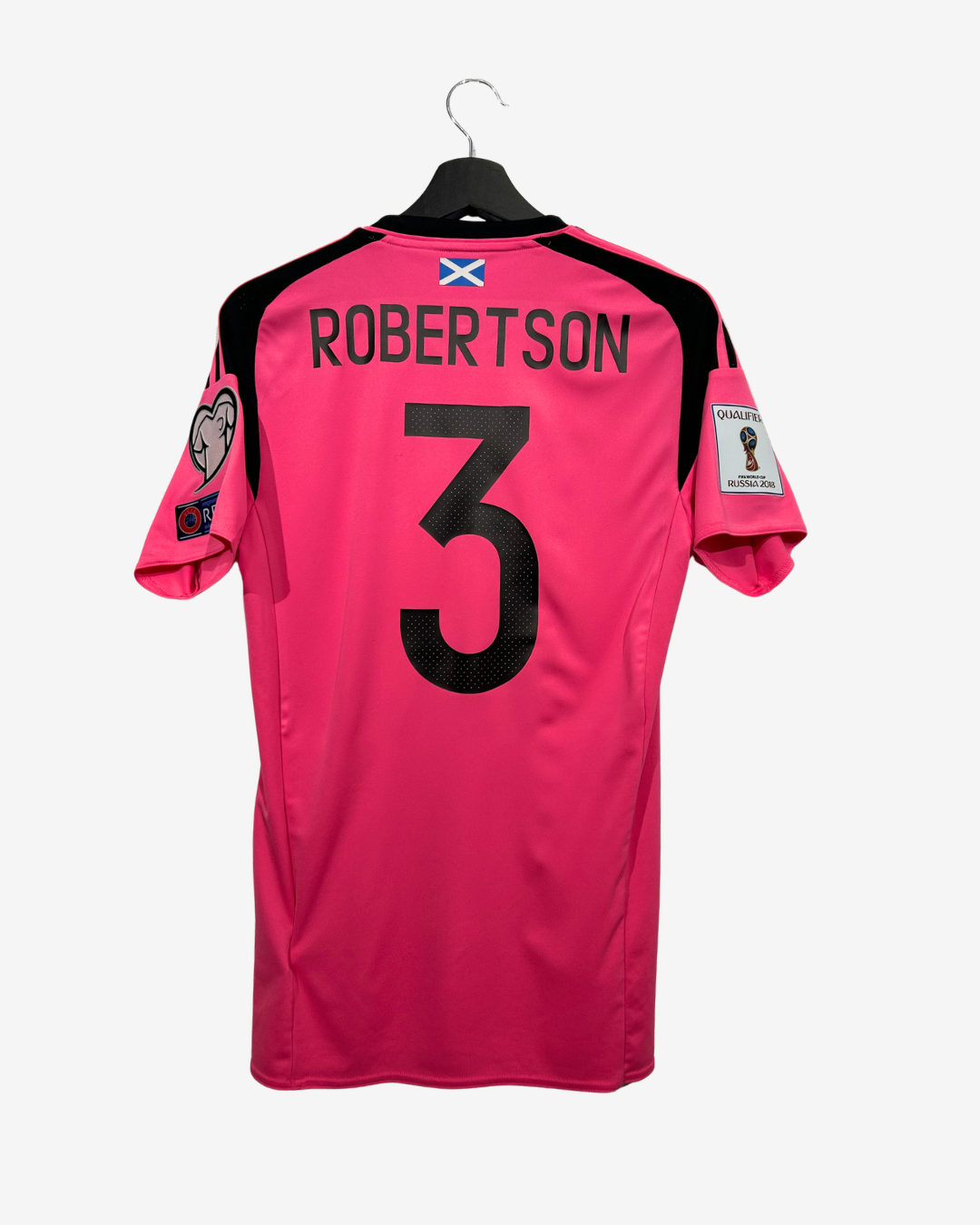 A bright pink Scotland national football team jersey shown from the back on a black hanger. The back features the name 'ROBERTSON' and number '3' in black, with a small Scotland flag patch near the collar and two sleeve patches.