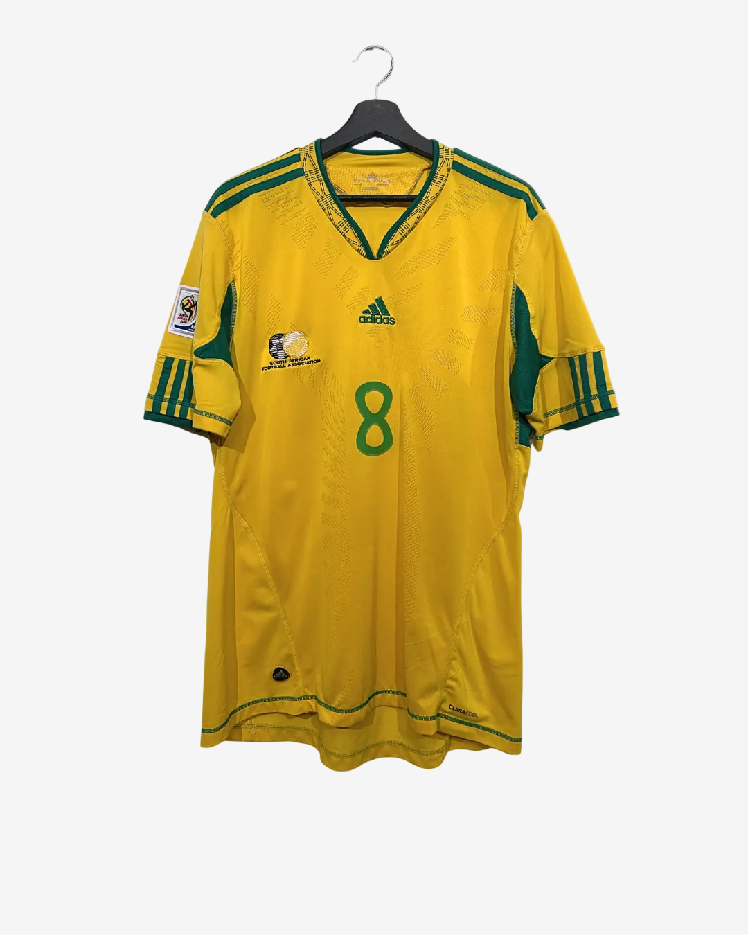Yellow soccer jersey with green accents on a hanger against a white background