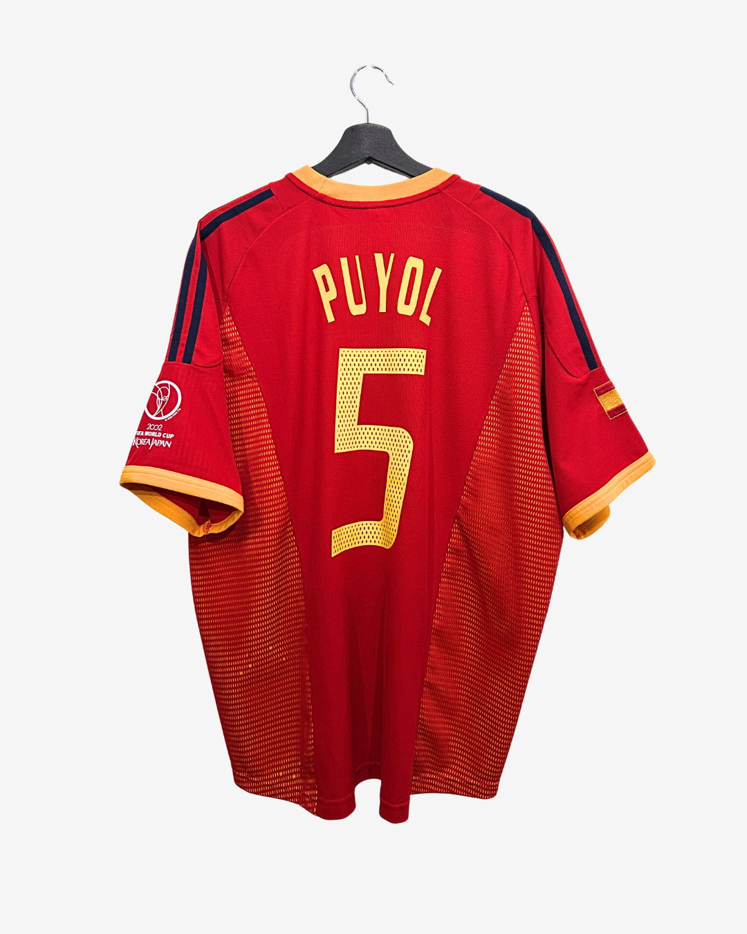 Red sports jersey with 'Puyol' and number '5' on a hanger against a white background