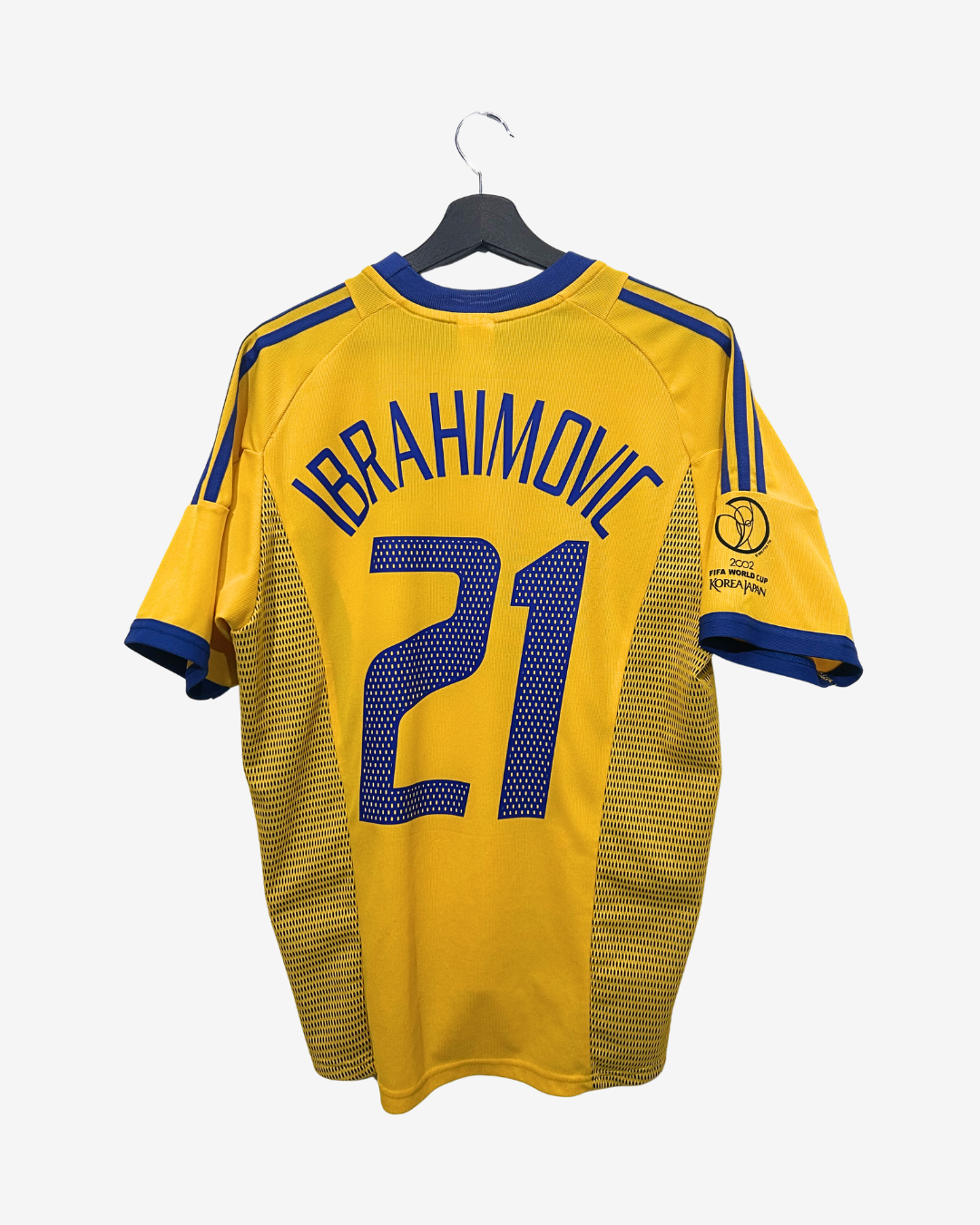 Yellow sports jersey with 'Ibrahimovic 21' on a hanger against a white background