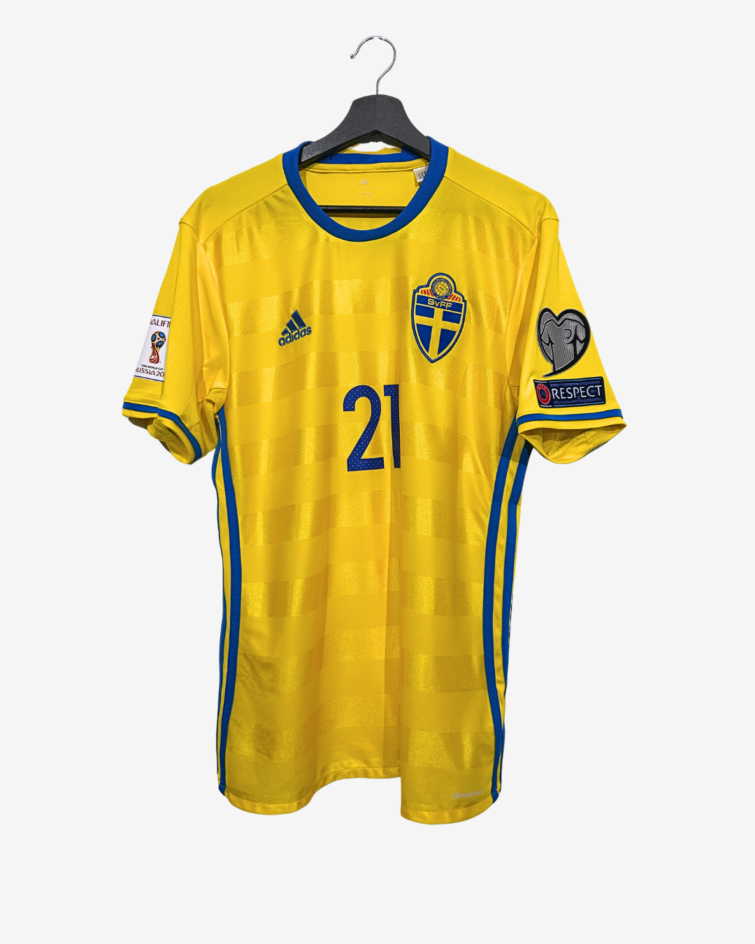 Yellow sports jersey with number 21 on a hanger against a white background