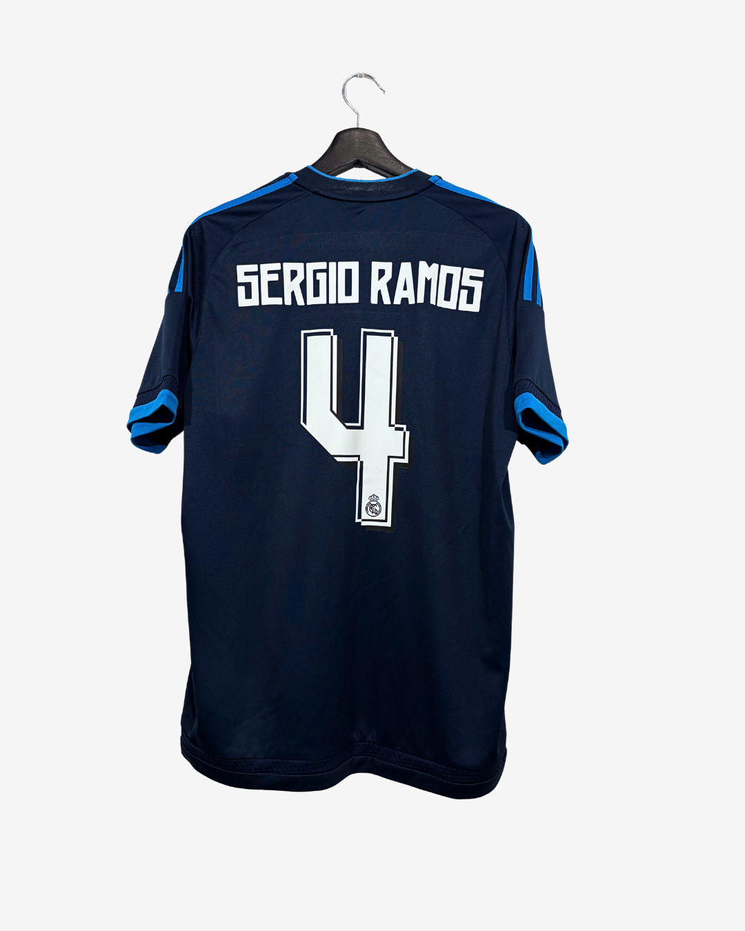 A dark navy blue soccer jersey with 'SERGIO RAMOS' and the number '4' printed in white on the back, hanging on a black hanger against a light gray background.