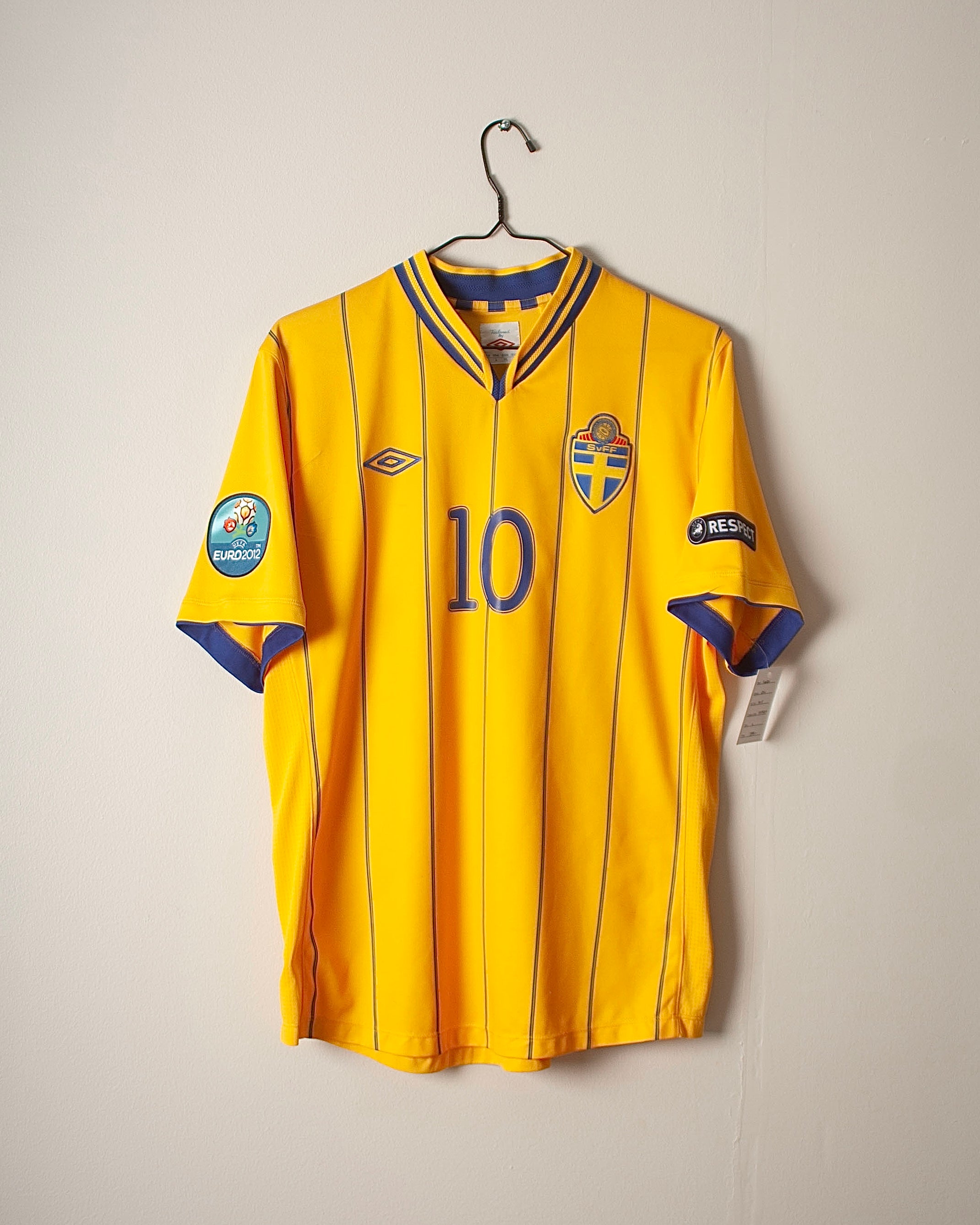 Yellow sports jersey with number 10 on a hanger against a plain background