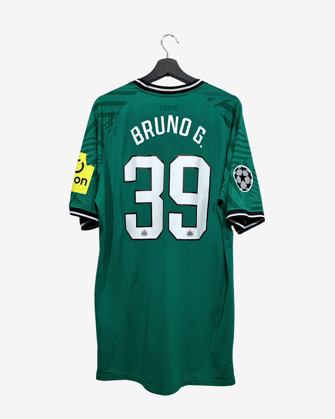 A green soccer jersey with 'BRUNO G.' and the number '39' on the back, hanging on a black hanger against a light gray background.