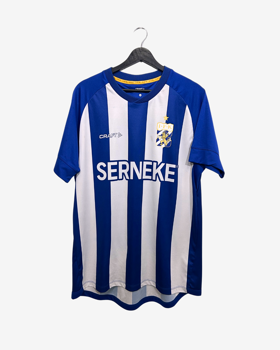 Blue and white striped sports jersey with 'Craft' and 'Serneke' logos on a hanger against a white background.