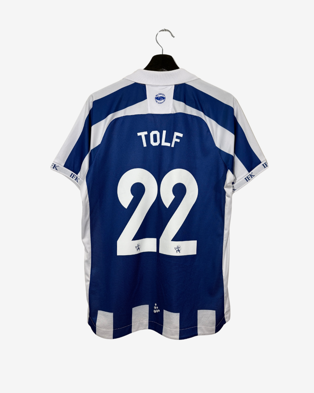 Back view of a blue and white football jersey hanging on a black hanger against a light gray background. The jersey has 'TOLF' and the number '22' printed in white on the back.