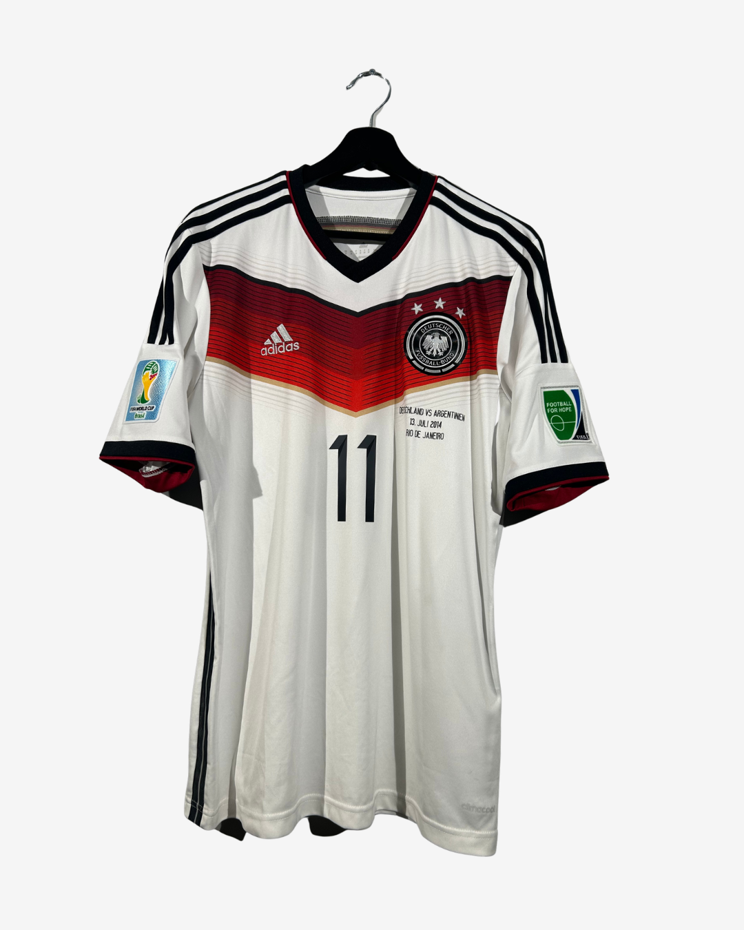 A white Adidas Germany national football team jersey with a red and black chest stripe, black shoulder stripes, the number 11 on the front, and World Cup patches on the sleeves, hanging on a black hanger against a light gray background.