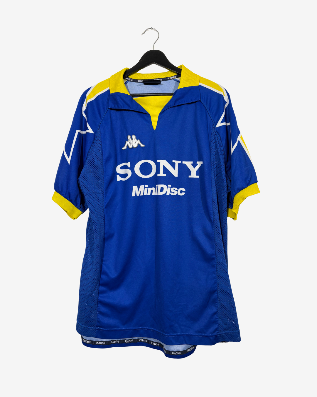 A vintage blue and yellow Kappa soccer jersey with 'SONY MiniDisc' printed on the front, hanging on a black hanger against a light gray background.