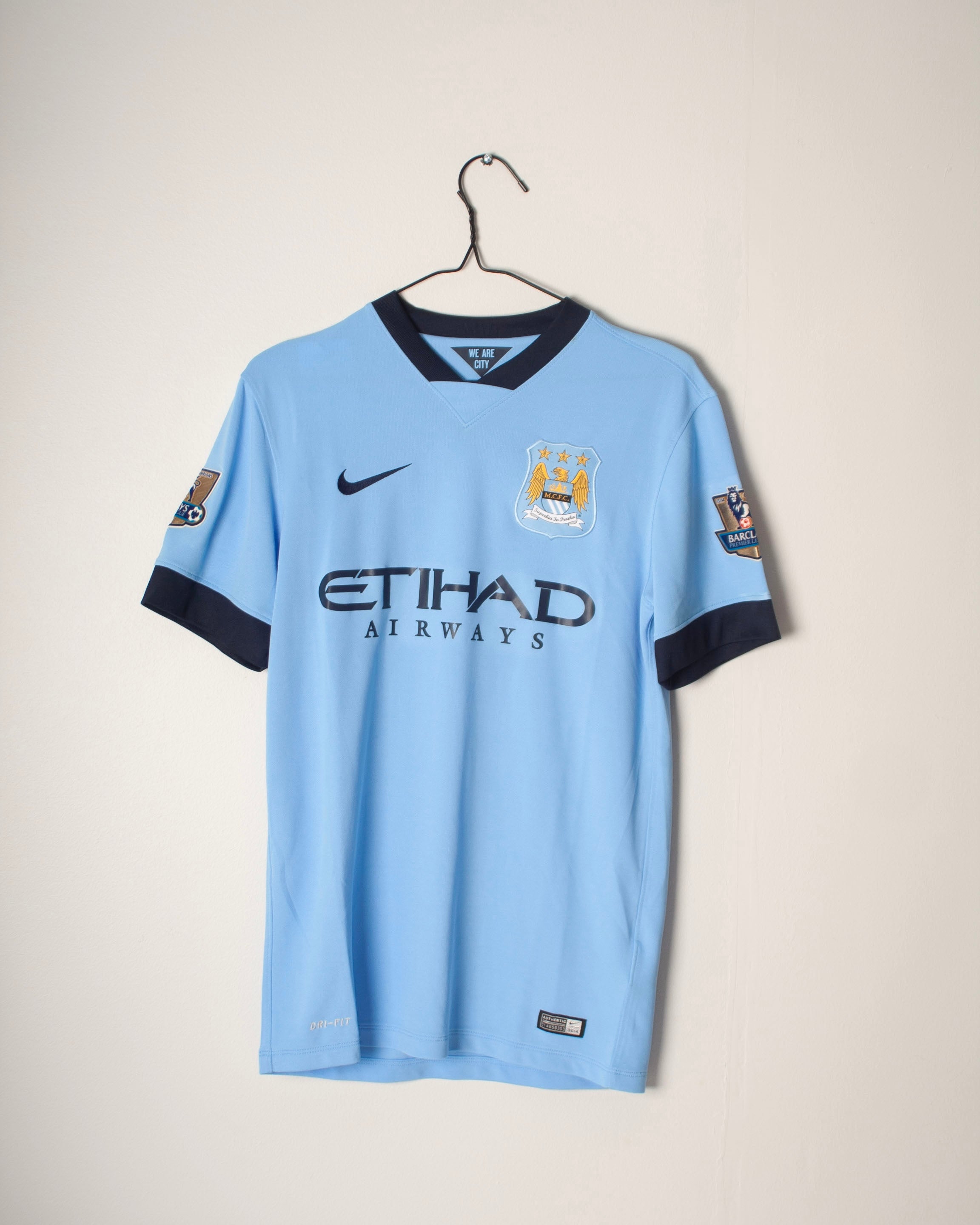“Manchester City 2014/15 hemmatröja i blått designad av Nike – framsida med klubbens emblem.”
