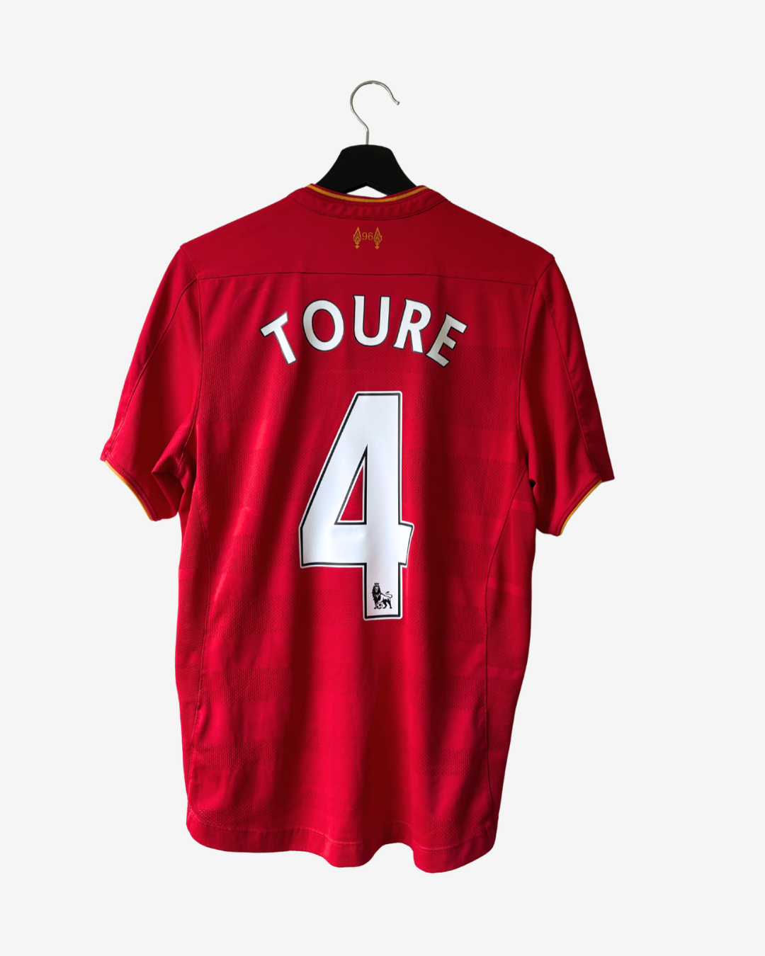 A red short-sleeve soccer jersey hanging on a black hanger against a light gray background. The back of the shirt features the name 'TOURE' and the number '4' in white with black outlines.