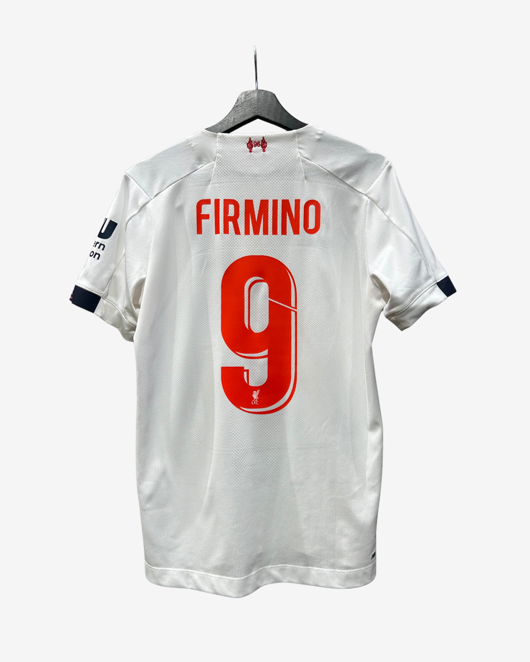 White football jersey shown from the back on a hanger, with 'FIRMINO' and the number 9 printed in red. Under Armour logo is visible at the inner neck.