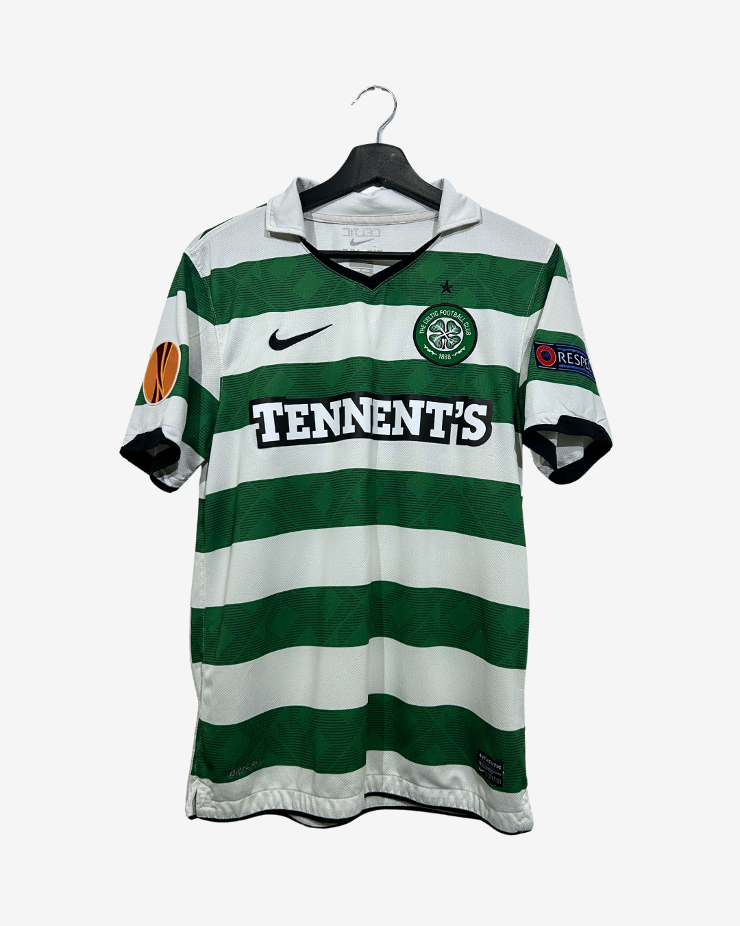 A vintage Celtic FC home soccer jersey with green and white stripes, featuring 'TENNANT'S' across the chest, a black Nike swoosh, and a black hanger against a light gray background.