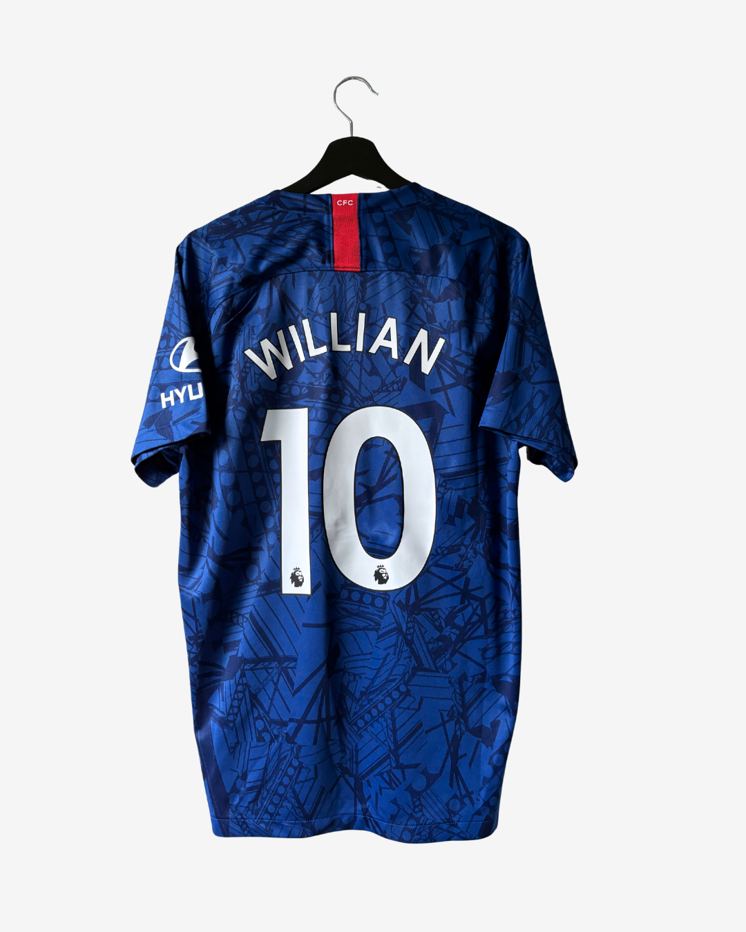 Back view of a blue short-sleeve soccer jersey hanging on a black hanger against a light gray background. The jersey has 'WILLIAN' and the number '10' in white on the back, with a red neck label and a sponsor logo on the sleeve.