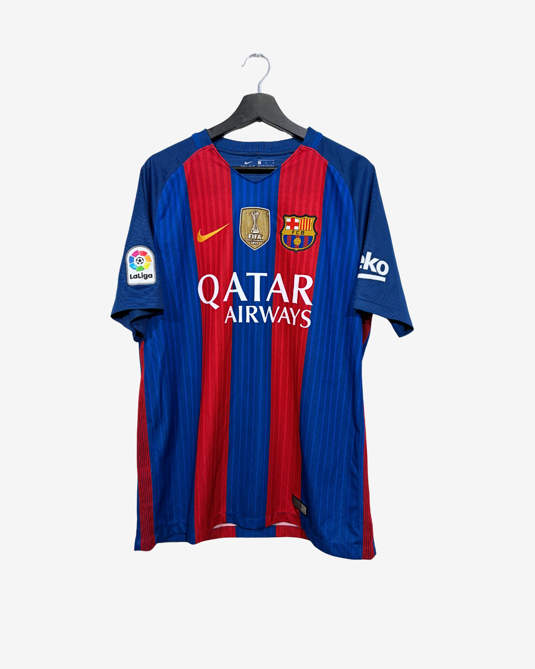 FC Barcelona home soccer jersey with blue and red vertical stripes, featuring the Nike swoosh, FC Barcelona crest, and Qatar Airways sponsor logo, hanging on a black hanger against a light gray background.