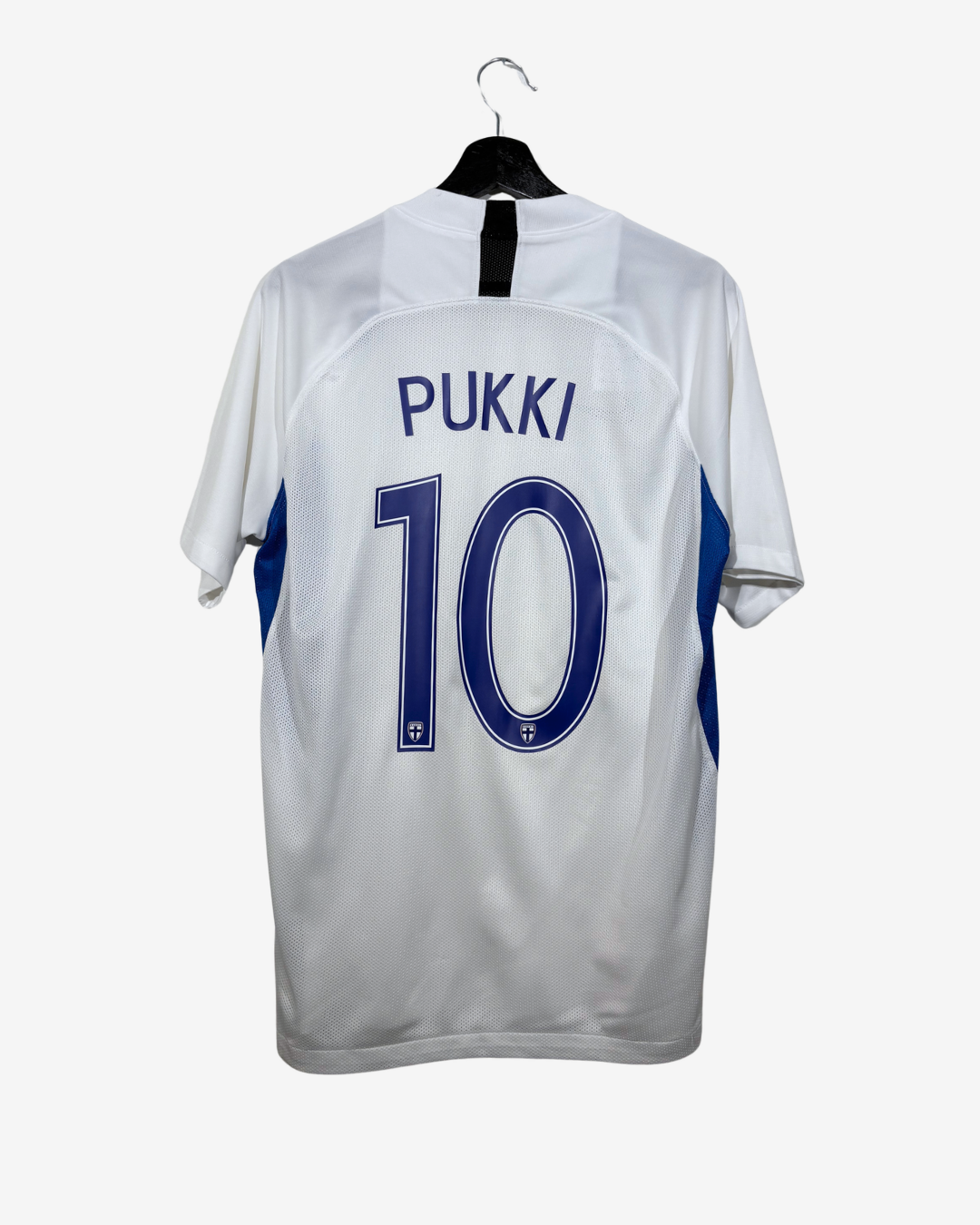 White short-sleeve soccer jersey shown from the back on a black hanger, with 'PUKKI' and the number '10' printed in blue, plus blue side panels.