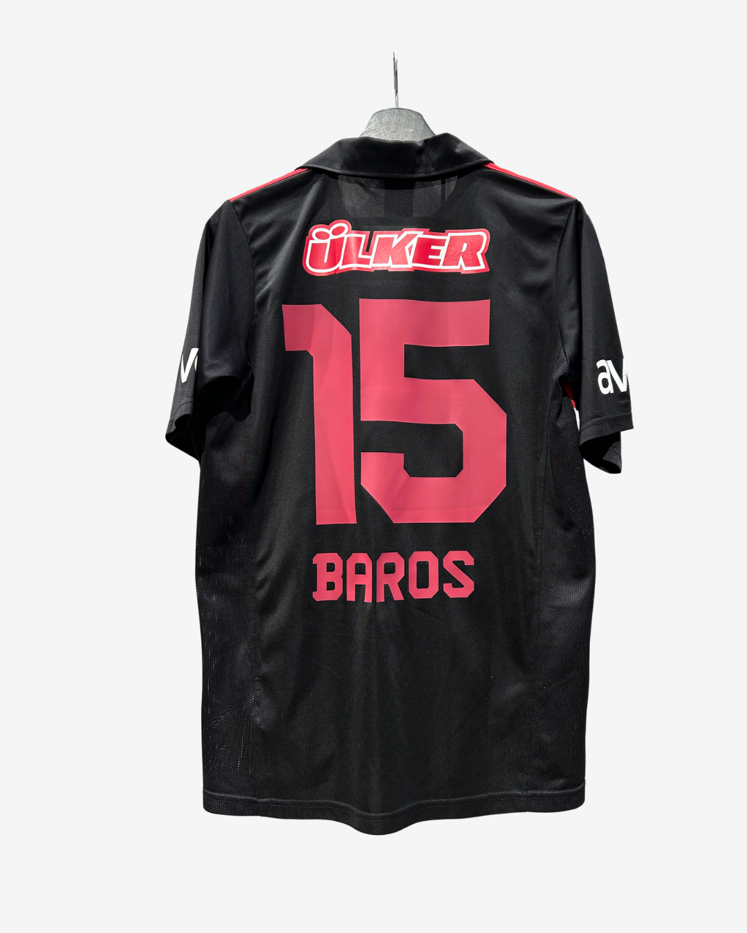 Black soccer jersey shown from the back on a hanger, featuring the name 'Ulker' in red and white above a large red number '15' and 'Baros' below in red.