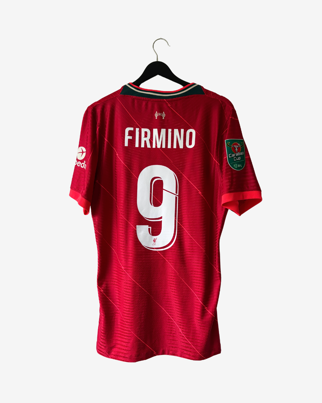 A red Liverpool FC soccer jersey with 'FIRMINO' and the number '9' printed on the back, hanging on a black hanger against a light gray background.