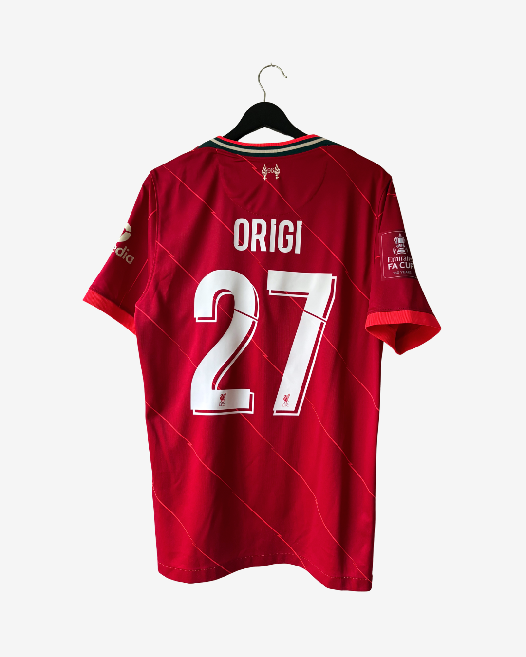A red short-sleeve soccer jersey hanging on a black hanger against a light gray background. The back of the jersey shows the name ORIGI and the number 27 in large white letters, with subtle diagonal red pinstripes across the fabric.
